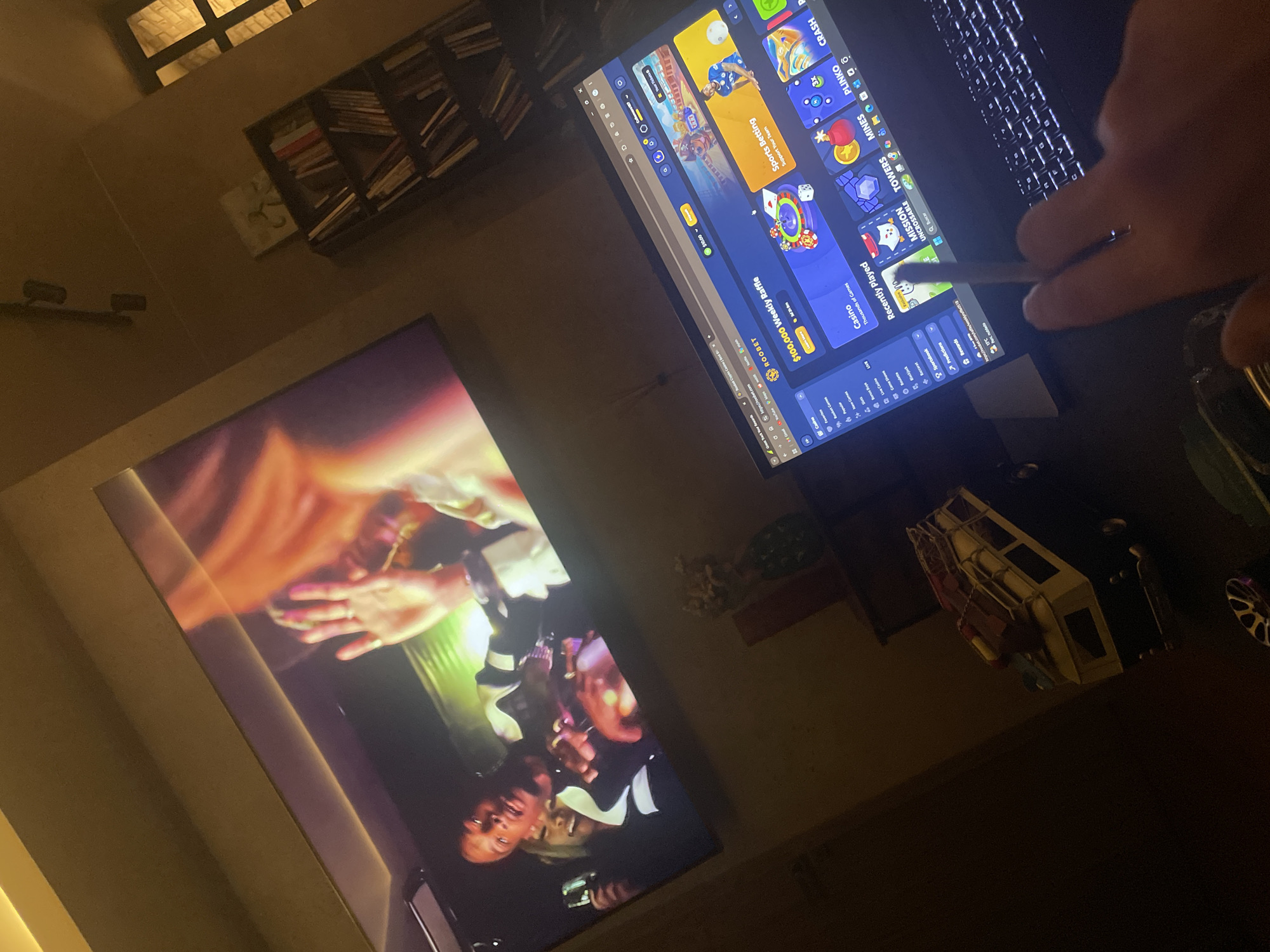 The image shows a laptop displaying the website Roobet with a hand holding what appears to be a cigarette next to the keyboard. A large screen displays what looks like a wedding scene with the groom visible. In the background is a bookshelf. The image provides no verifiable information to pinpoint it to Huixquilucan de Degollado, Mexico.