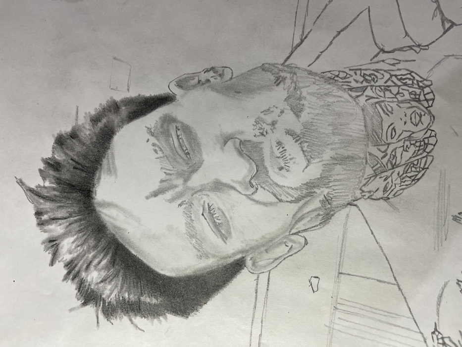 This image is a monochrome pencil drawing rendered on white paper, depicting a head-and-shoulders portrait of a male individual. The subject is presented in a close-up, slightly upward-angled view, suggesting a selfie-like perspective. The male figure has short, spiky, dark hair and a beard or heavy stubble covering his chin and jawline. His eyes are depicted as partially closed or squinting, with prominent eyelids and subtle lines around the eyes. His mouth is pursed in a distinct expression. A complex, detailed tattoo is visible on his neck, featuring multiple stylized faces and intricate patterns. The outline of a collar or a jacket is discernible around his shoulders. The drawing itself is the subject, existing on a blank, light-colored surface, presumably paper, with no discernible background environment depicted within the artwork. There is no specific physical location in the city of Jos, Nigeria, or any other city, depicted or identifiable within this drawing.