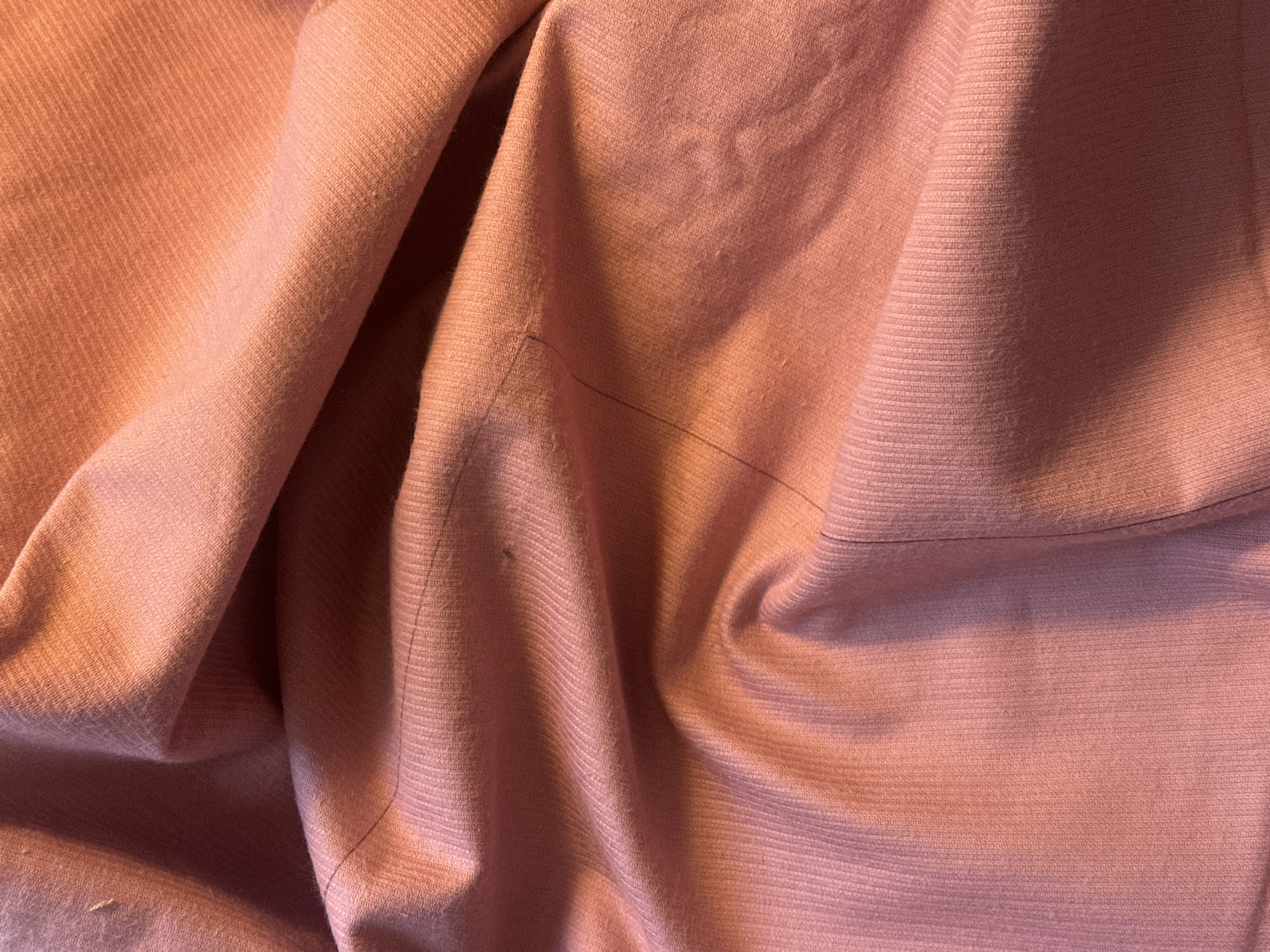 The image shows a close-up of wrinkled, light pink corduroy fabric. The texture is visible, with the raised ridges of the corduroy running horizontally across the frame. The folds and creases of the material create variations in light and shadow. No people, identifiable objects, or location details are discernible. The image does not provide any information related to Buenos Aires, Argentina.
