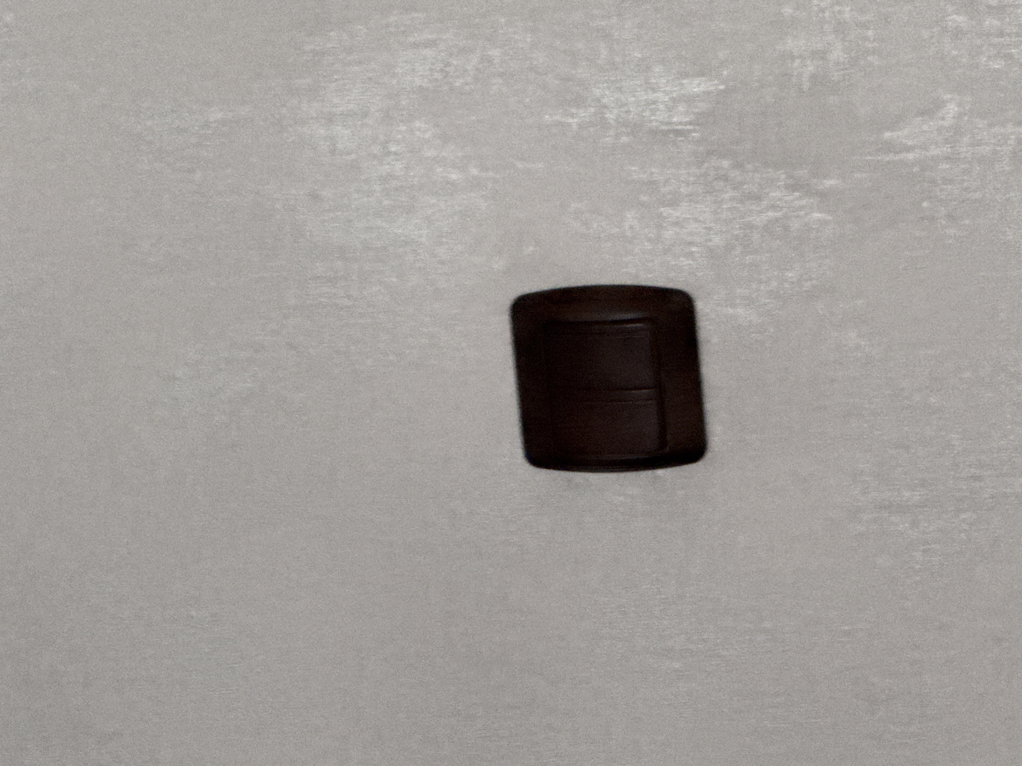 The image shows a dark brown, rectangular object on a light gray surface. The object appears to have a slightly glossy finish and a horizontal indentation or seam across its middle. The surface has a mottled texture. The location is not identifiable in the image and there is no indication that it is in Lovech, Bulgaria.