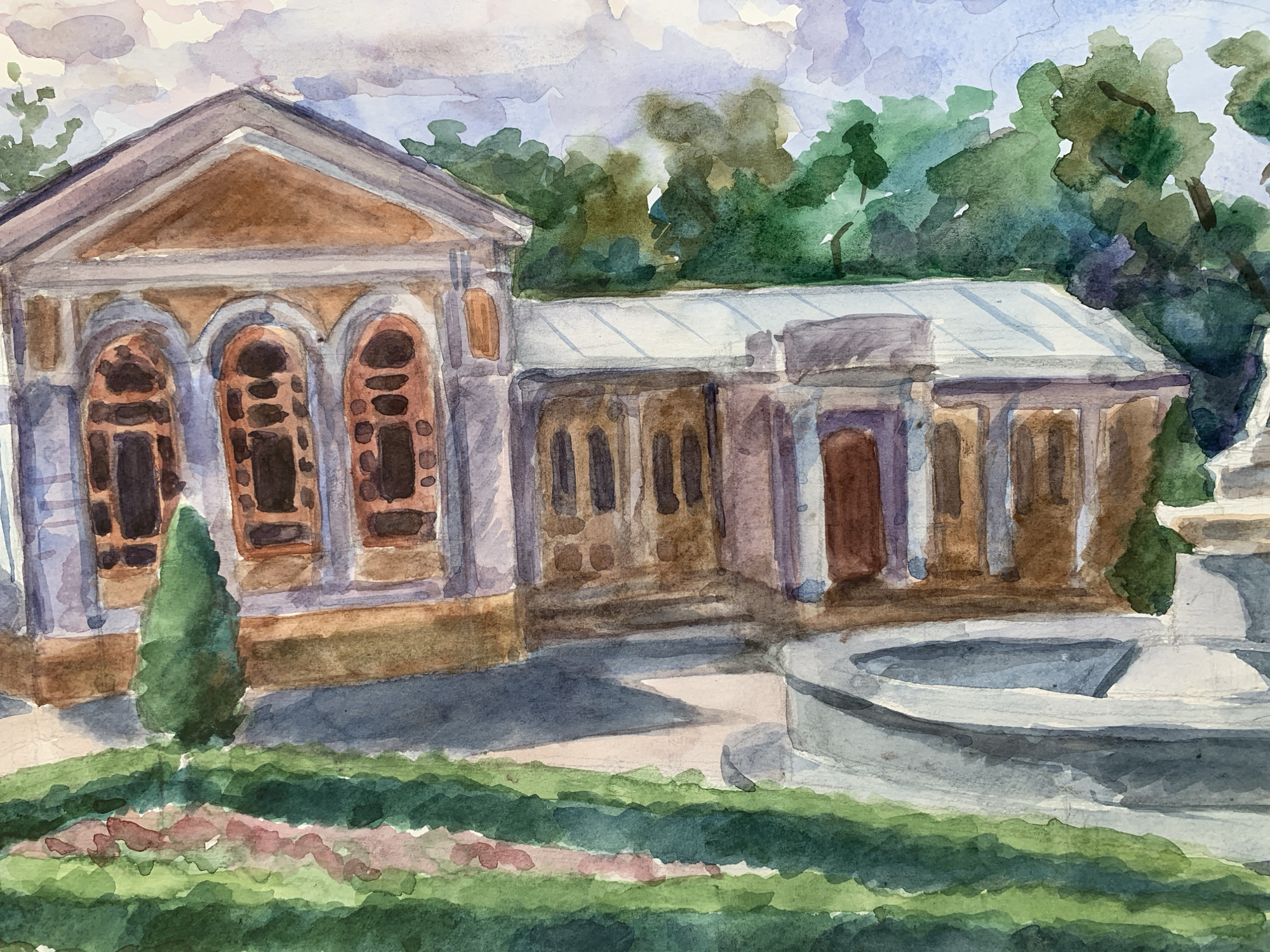 This is a watercolor painting depicting a building and its surroundings. The building is composed of two connected sections. The first section has a triangular roof and three arched windows. The second section has a flat roof and smaller rectangular windows. There is a small, cone-shaped tree beside the first section. A fountain is visible to the right of the second section. The foreground is filled with greenery. The sky is light blue with patches of white and gray. The location is Chaikovsky, Russia.