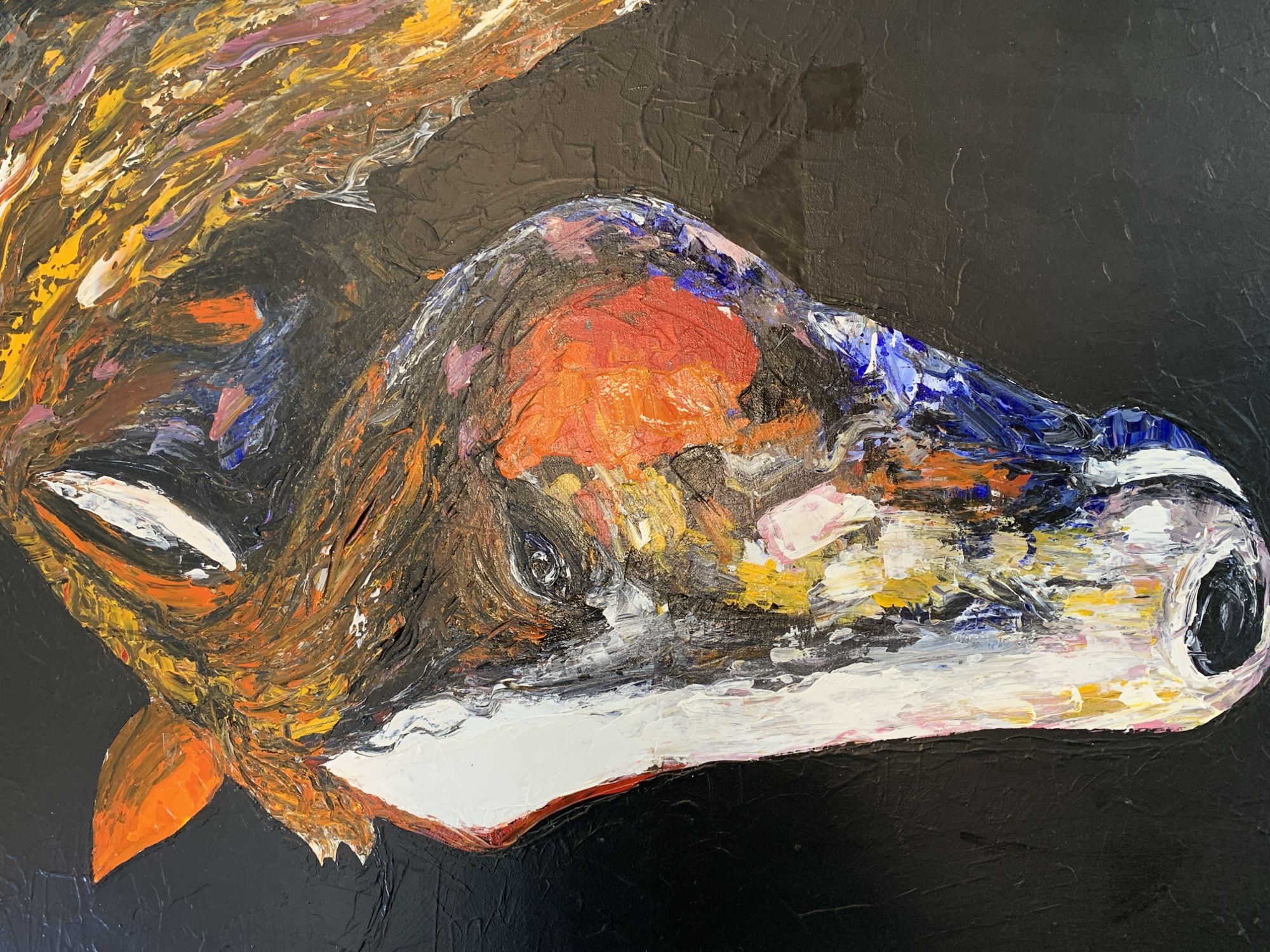 This image is a vertical photograph of an abstract expressionistic oil painting depicting a horse's head in profile, facing left. The painting is characterized by a heavy impasto technique, with thick, textured applications of paint. The background is a uniformly textured black. The horse's head features a stark white blaze running down its face. The visible eye is rendered with fragmented strokes of black, white, and blue. The mane, flowing behind the head, is composed of vibrant, textured strokes in shades of orange, yellow, brown, purple, and white. An orange ear is visible on the upper left. The muzzle shows white, pink, and blue tones, ending in a dark nostril. The painting is located in Moba, Nigeria.
