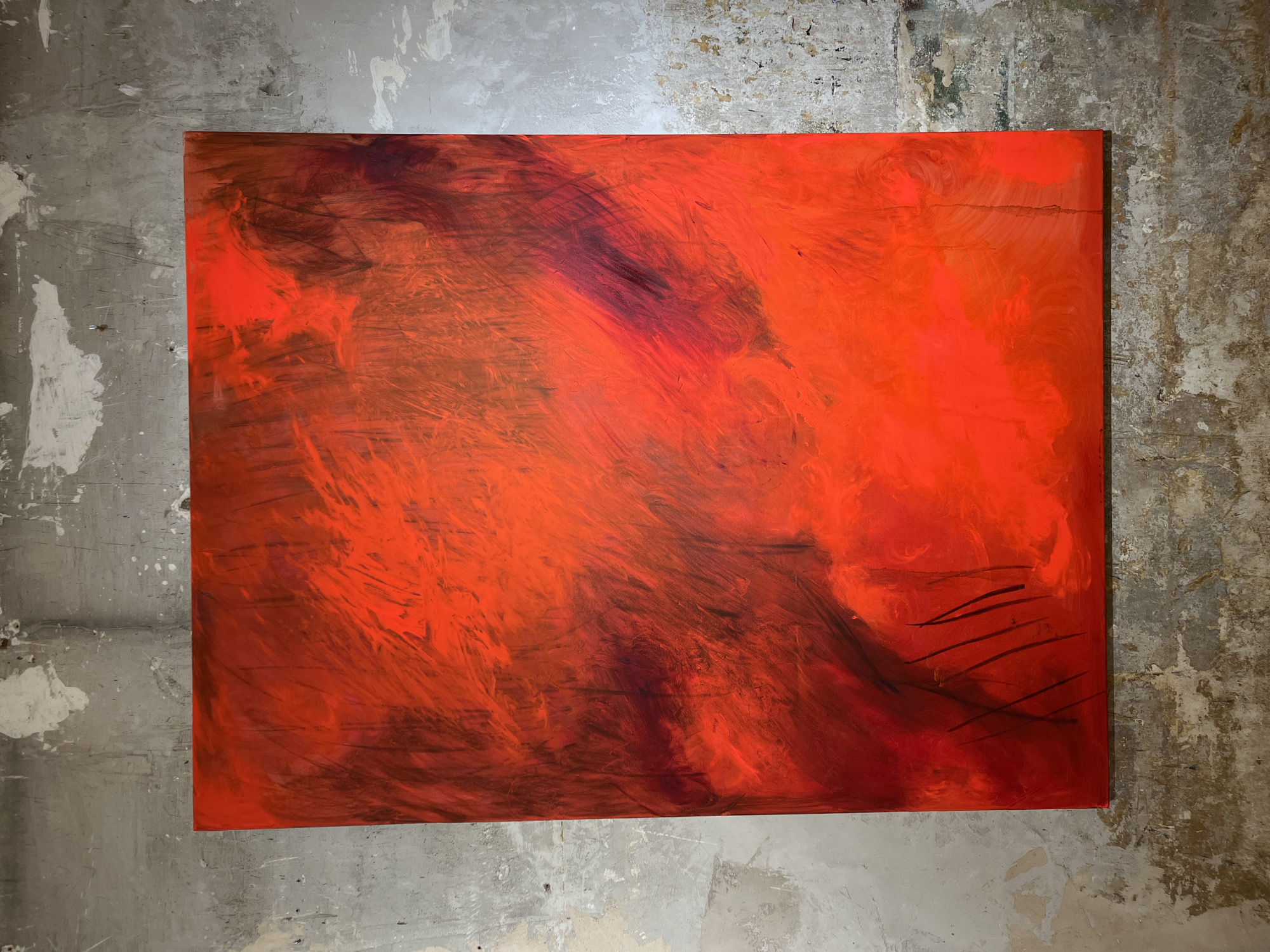 An abstract, rectangular painting predominantly featuring vibrant reds and oranges hangs on a distressed, concrete wall. The painting's surface exhibits energetic brushstrokes and variations in tone, suggesting depth and movement. Thin, dark lines are visible in the lower left quadrant of the painting. The wall itself is textured with patches of peeling paint and appears weathered, characteristic of an urban setting. The lighting is diffused, casting no strong shadows. The image does not contain any people or identifiable landmarks that would suggest a specific location in Barcelona, Spain.