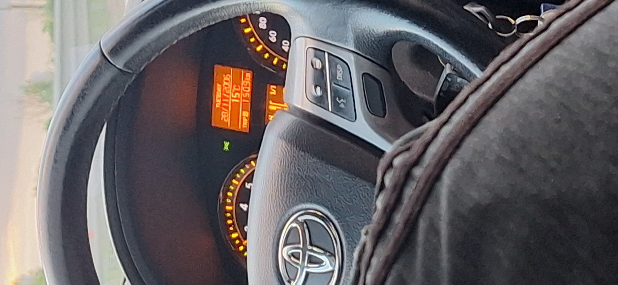 The image shows the interior of a Toyota car, specifically the steering wheel, dashboard, and instrument panel. The dashboard display indicates that the date is Tuesday, November 28, 2006, the temperature is 15 degrees Celsius, and the trip distance is 150.9 km. The car's engine is running, as indicated by the illuminated gauges. A person is sitting in the driver's seat. The location in the city of Studena, Bulgaria, cannot be confirmed solely based on this image.
