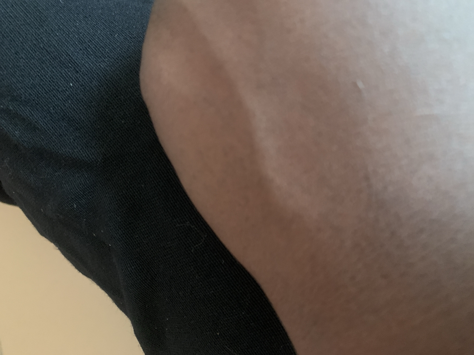 The image displays a close-up view of a person's arm, covered partially by a black garment. The skin tone is medium brown, and there are visible veins on the surface of the arm, suggesting it is likely resting or bent. The background is a plain, light-colored wall. There is no discernible connection to the city of Jauro Yinu, Nigeria, as the image lacks any geographical indicators or context that would place it in that location.