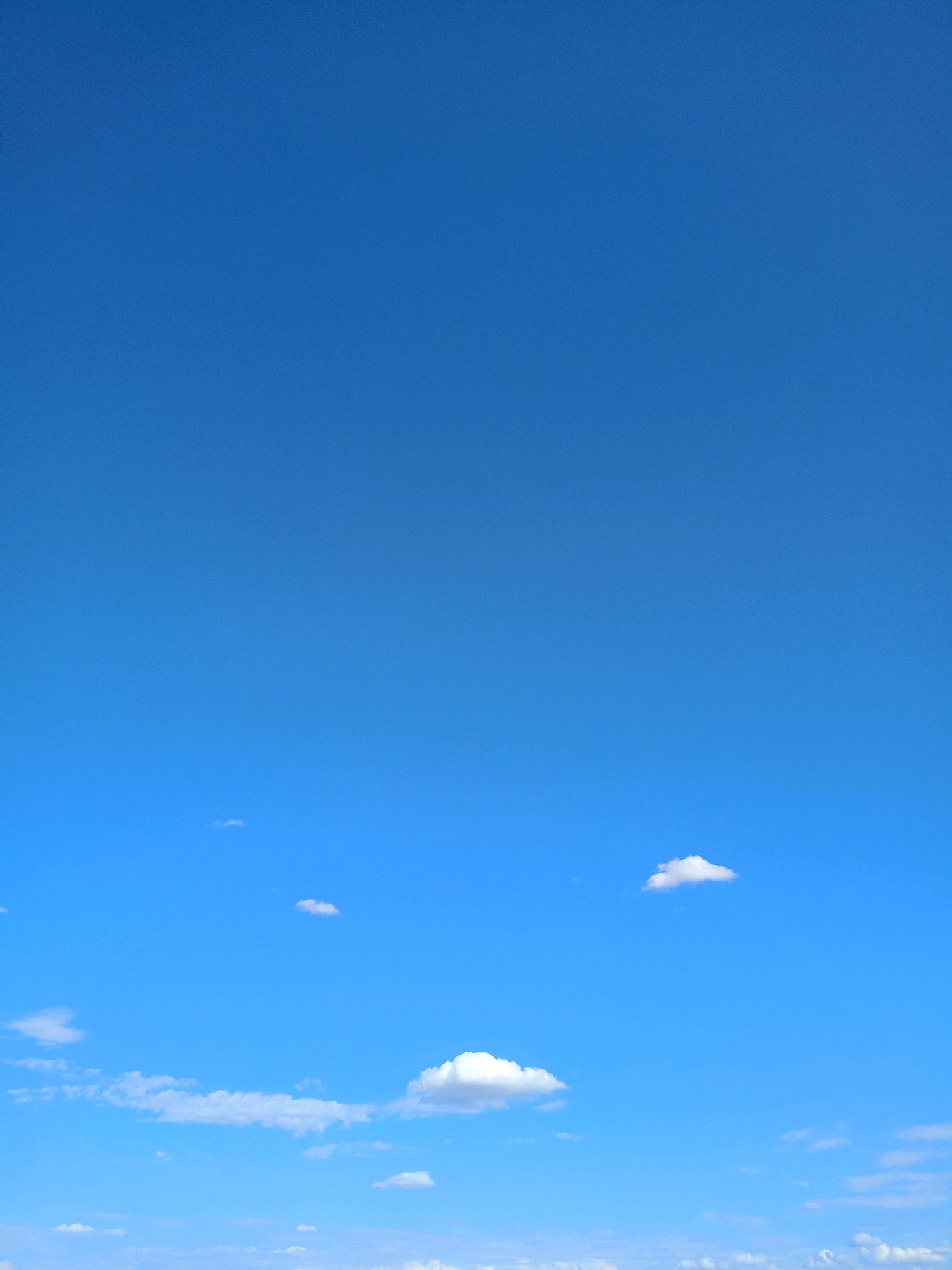 The image shows a clear blue sky with a few scattered white clouds. There is no sign of the city of Baurci, Moldova, or any people, subjects, objects, or actions. The environment is purely atmospheric.