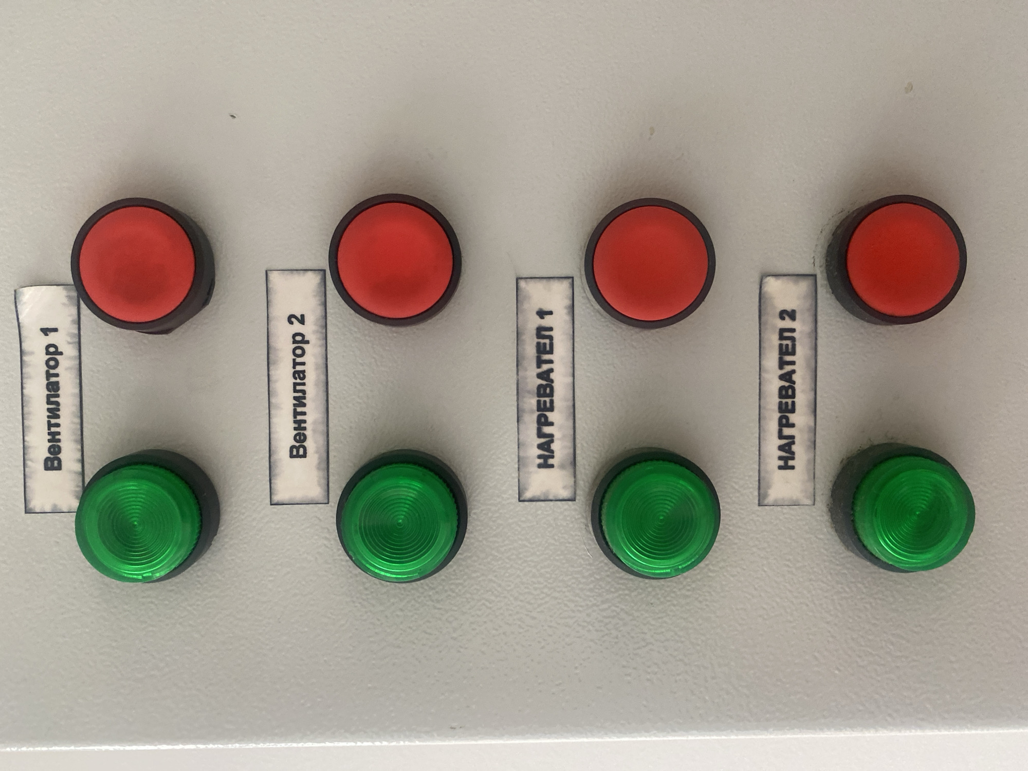 A control panel features four pairs of red and green circular buttons, each paired with a label. The labels read "Вентилатор 1," "Вентилатор 2," "НАГРЕВАТЕЛ 1," and "НАГРЕВАТЕЛ 2," respectively, from left to right. The environment is devoid of other discernible details. There are no people visible. The location is presumed to be in Sofia, Bulgaria, based on the Cyrillic text on the labels.