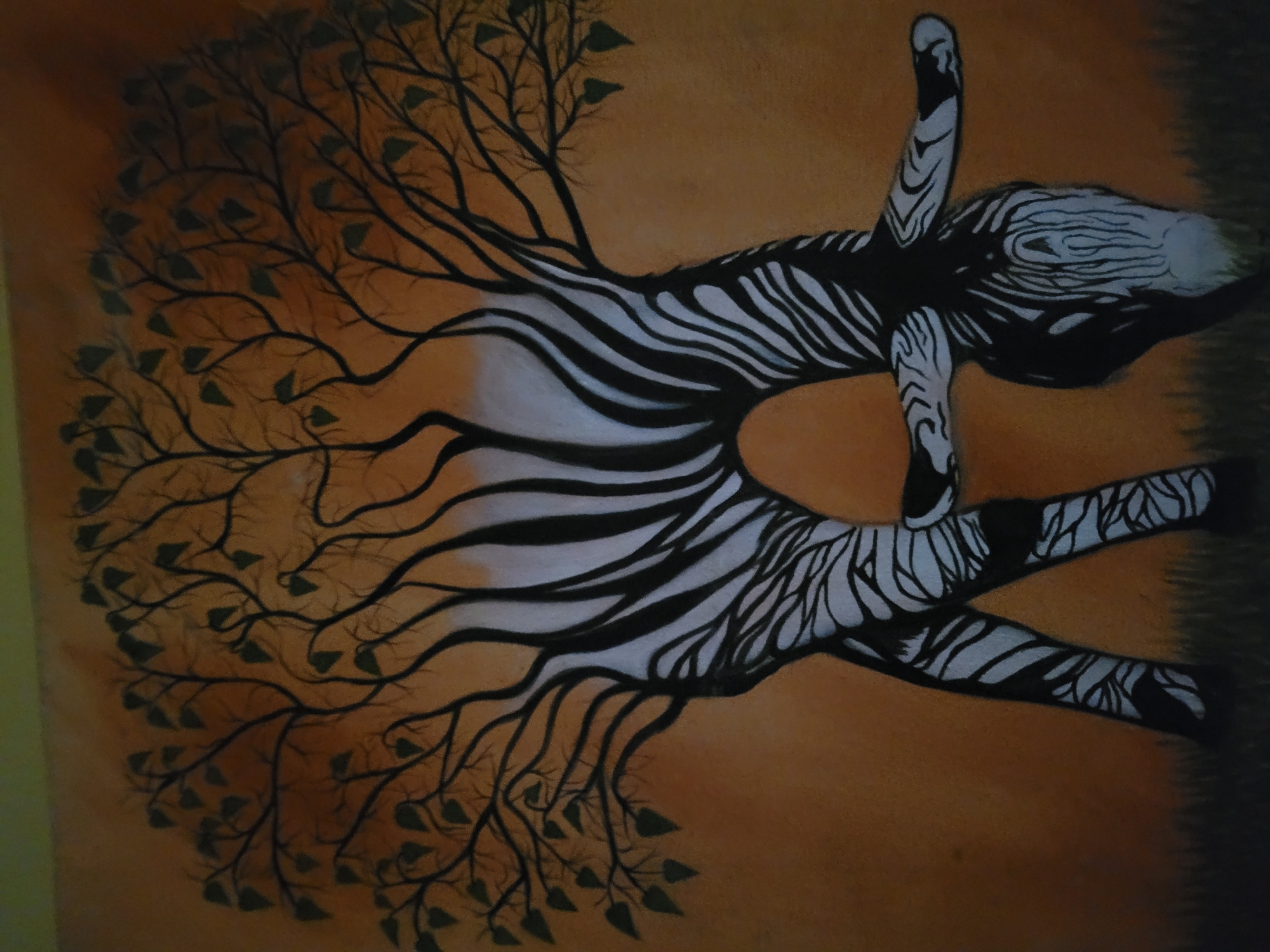 The image is an artistic representation of a zebra-like figure with tree branches and leaves emanating from its body. The figure is depicted with black and white stripes reminiscent of a zebra, but its form is more abstract and human-like with arms and legs extended. The tree branches grow outward from the torso area, and the leaves are dark. The background is a gradient of orange and brown. The location is Unknown, Unknown.