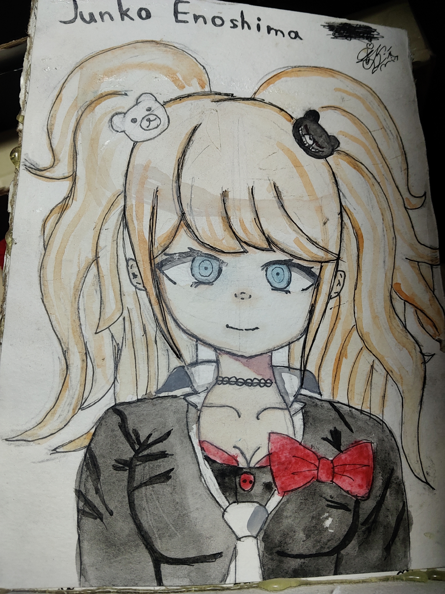 The image is a drawing on paper of a young woman with blonde pigtails, blue eyes, and a black jacket with a red bowtie. She has two bear-shaped accessories in her hair. The drawing is signed "Junko Enoshima" at the top. There is no discernible information about the city of Kharkiv, Ukraine, in the image.