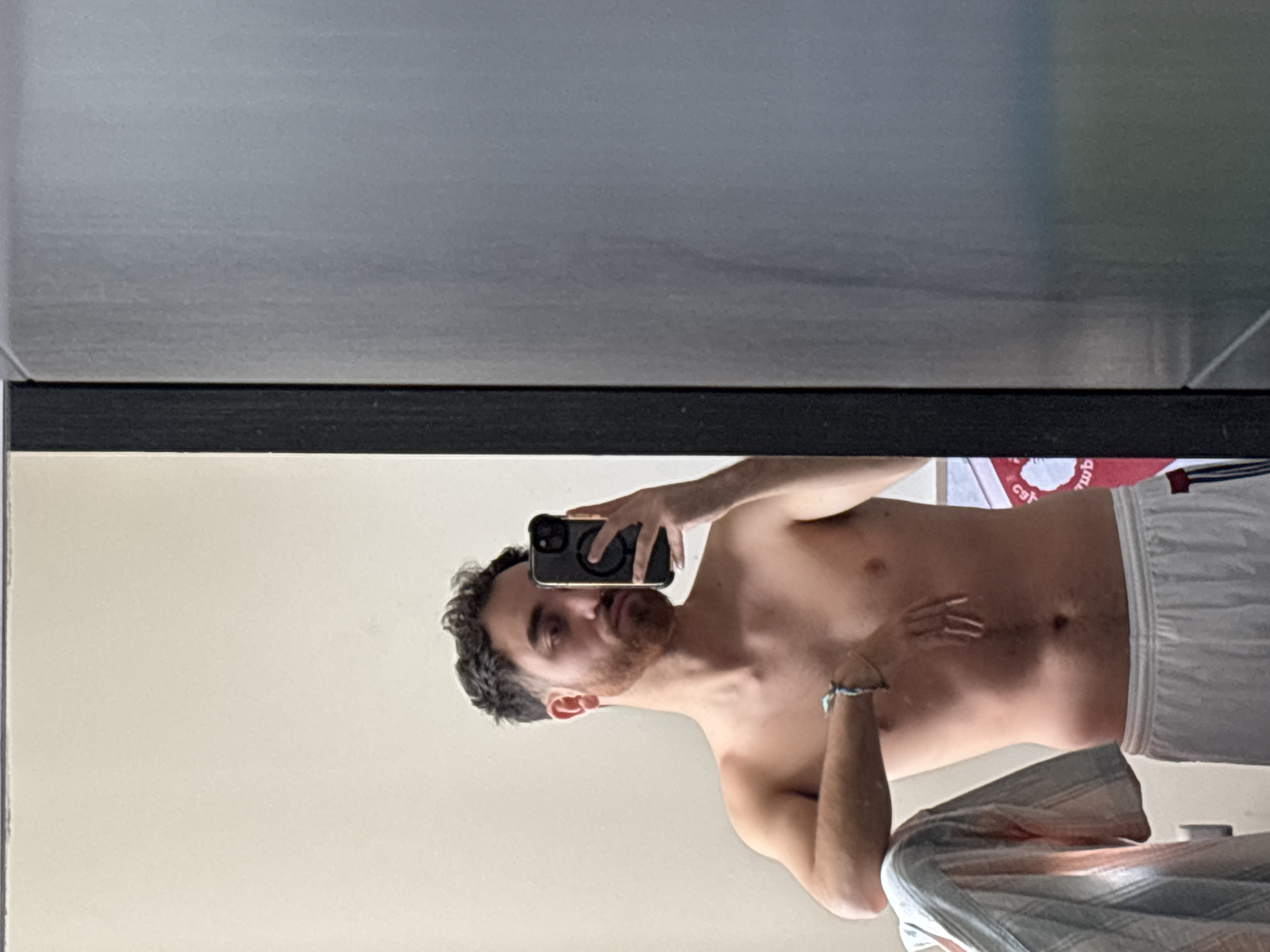 A shirtless man is taking a selfie in a mirror. The location is unclear. There is no verifiable information suggesting the photo was taken in Santa Clara Ocoyucan, Mexico.