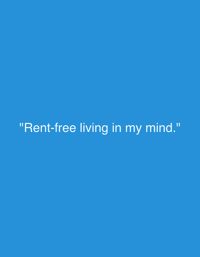 The image is a plain blue background with the text "Rent-free living in my mind." in white, centered in the frame. There is no discernible location, city, people, subjects, objects, actions, interactions, or environment beyond the described background and text.