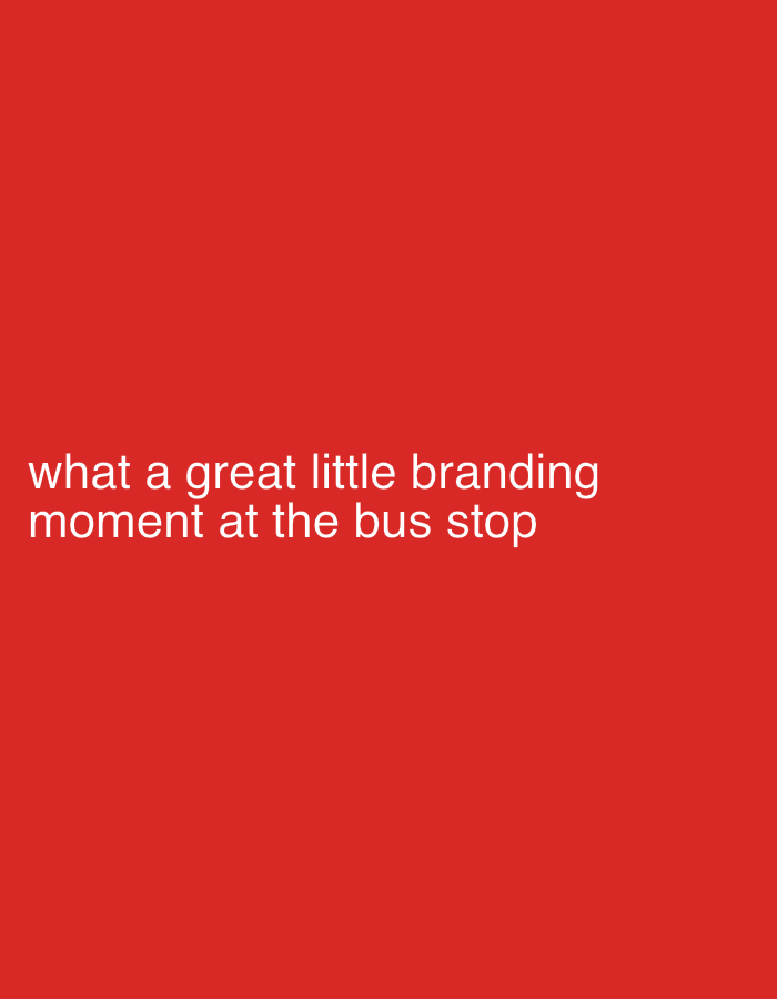 The image is a close-up of a red surface with the text "what a great little branding moment at the bus stop" in white. The location in the city of London, United Kingdom, is not depicted in the image.