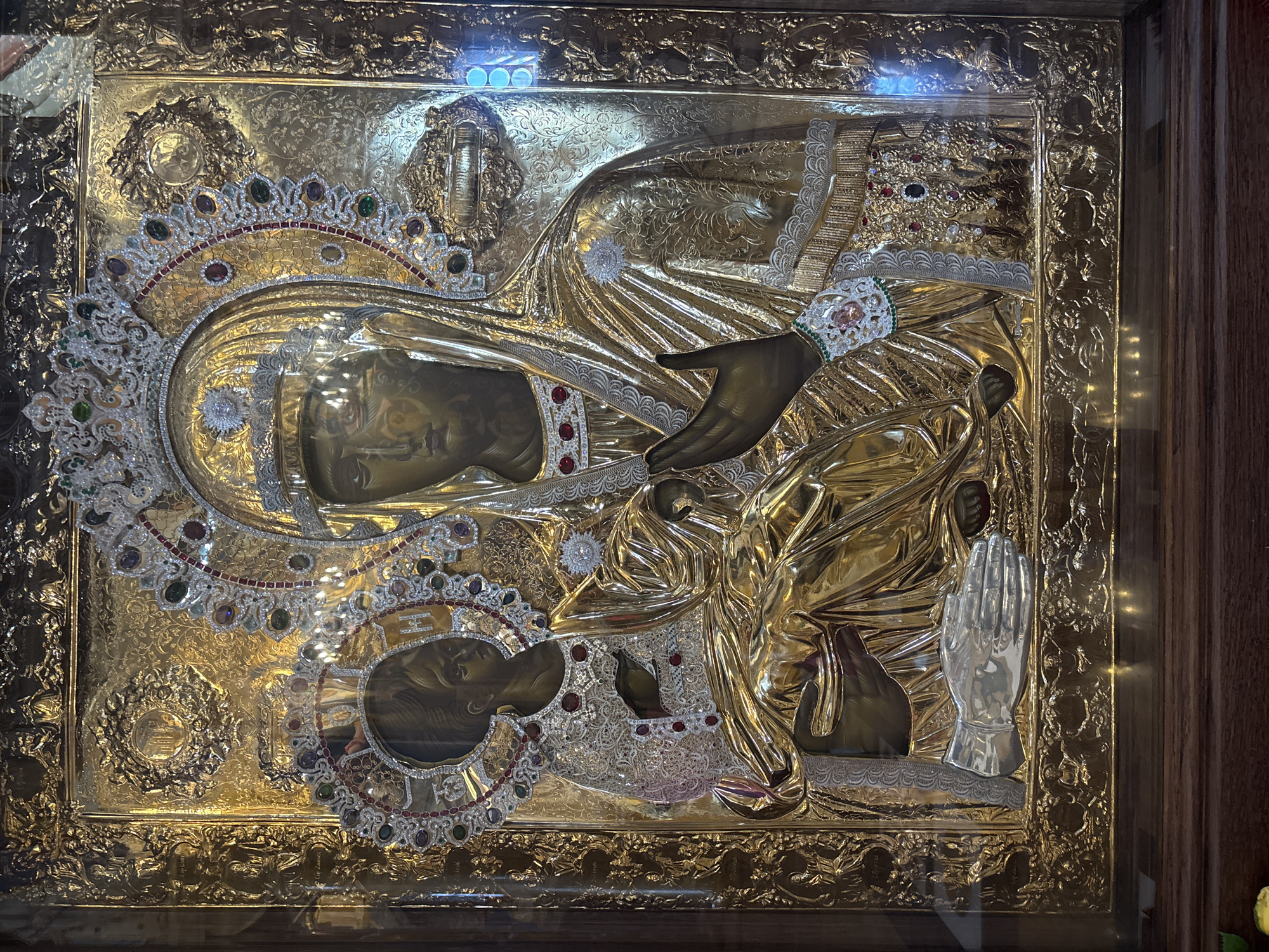 The image shows a gilded religious icon depicting the Virgin Mary with the infant Jesus. The icon is richly ornamented with precious stones and metalwork. It's a part of the collection inside the Church of St. Jovan Vladimir in Bar, Montenegro.