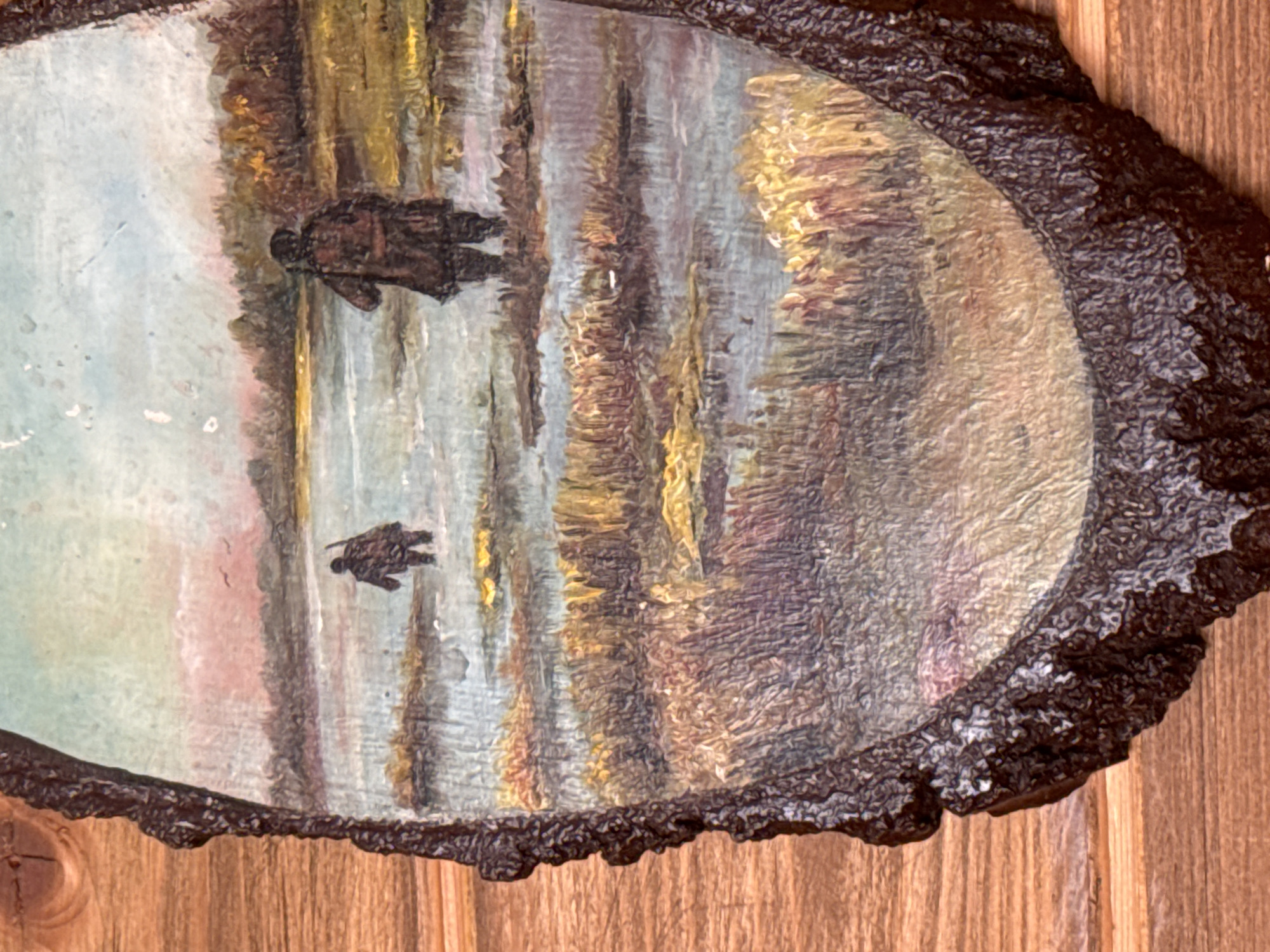 The image depicts a painting on a section of a tree trunk, likely a decorative piece. The painting represents a waterscape with figures that could be people or animals. The dominant colors are blues, browns, and yellows. The brushstrokes appear textured. The tree trunk section has a dark, rough bark around the edges. The background behind the artwork is a wooden surface. There is no evidence the image is located in Ketoshi, Russia.