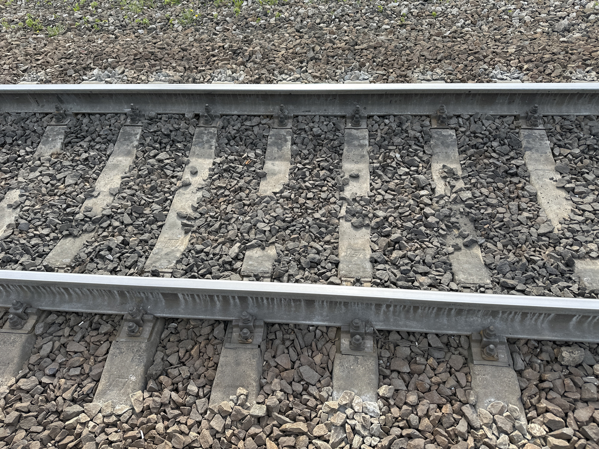 The image shows a section of railroad tracks. The tracks consist of two parallel steel rails resting on concrete sleepers, which are embedded in gravel ballast. The gravel fills the spaces between and around the sleepers. The location is likely near Кечёво, Russia.