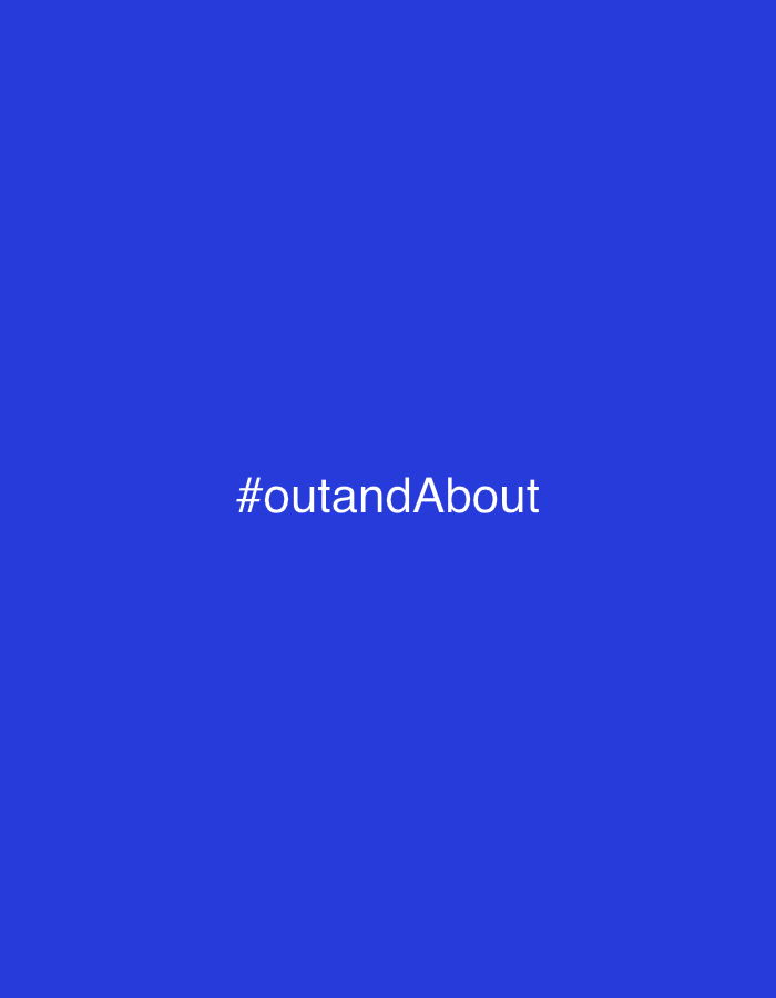 A white hashtag symbol is centered on a solid royal blue background. To the right of the hashtag symbol, the text "#outandAbout" is written in white.