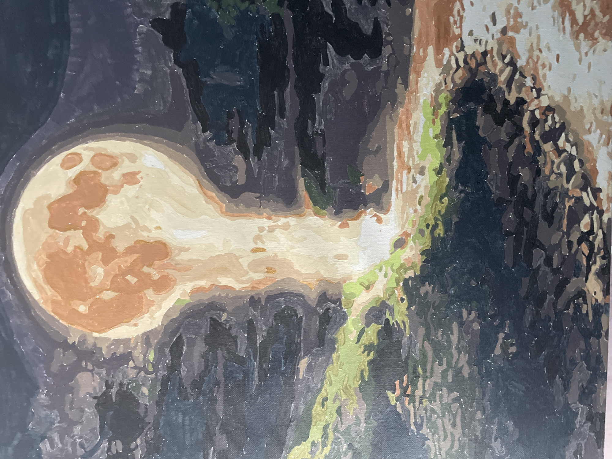 The image depicts a painting of a large, luminous full moon casting a bright beam of light downwards. The moon appears to be an unnatural, almost bulbous shape, colored in shades of orange and yellow, with darker circular markings. The light from the moon illuminates a path or riverbed covered in pebbles and some patches of green vegetation. The surrounding landscape is dark and shadowy, rendered in deep blues, purples, and blacks, suggesting a nighttime scene. The style is impressionistic, with visible brushstrokes and blocks of color. There are no people or specific landmarks visible that would indicate a location in Rivne, Ukraine.