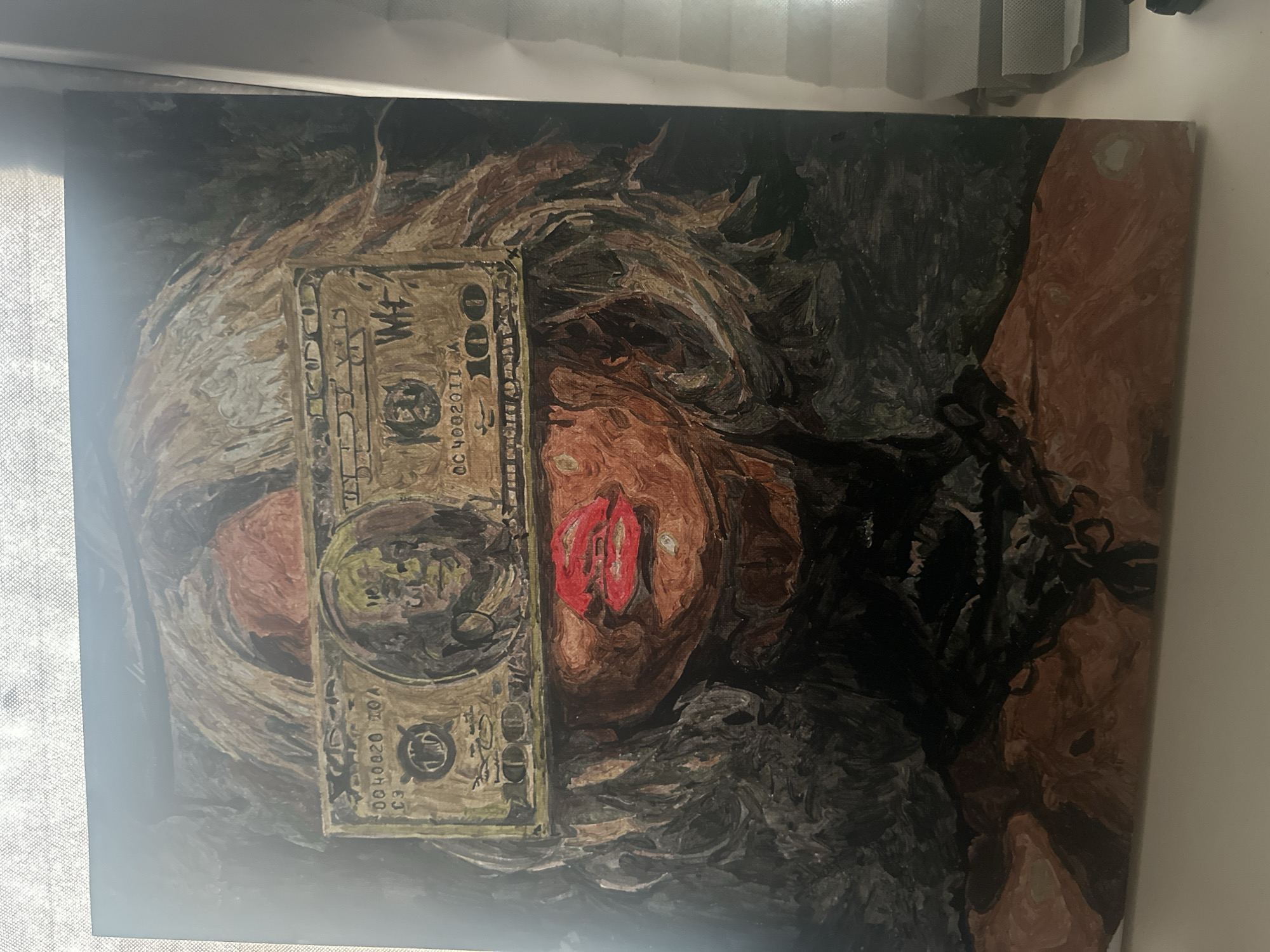 The image depicts an oil painting on canvas, laid horizontally. The painting portrays a woman with a 100-dollar bill obscuring her eyes. Her skin tone is a reddish-brown. Her lips are painted bright red. A mass of dark, indistinct matter is painted to the right of her face. The painting is leaning against a wall. The image appears to be taken indoors. The location is not discernible from the visual information provided and therefore Высокий, Russia, cannot be confirmed or denied.