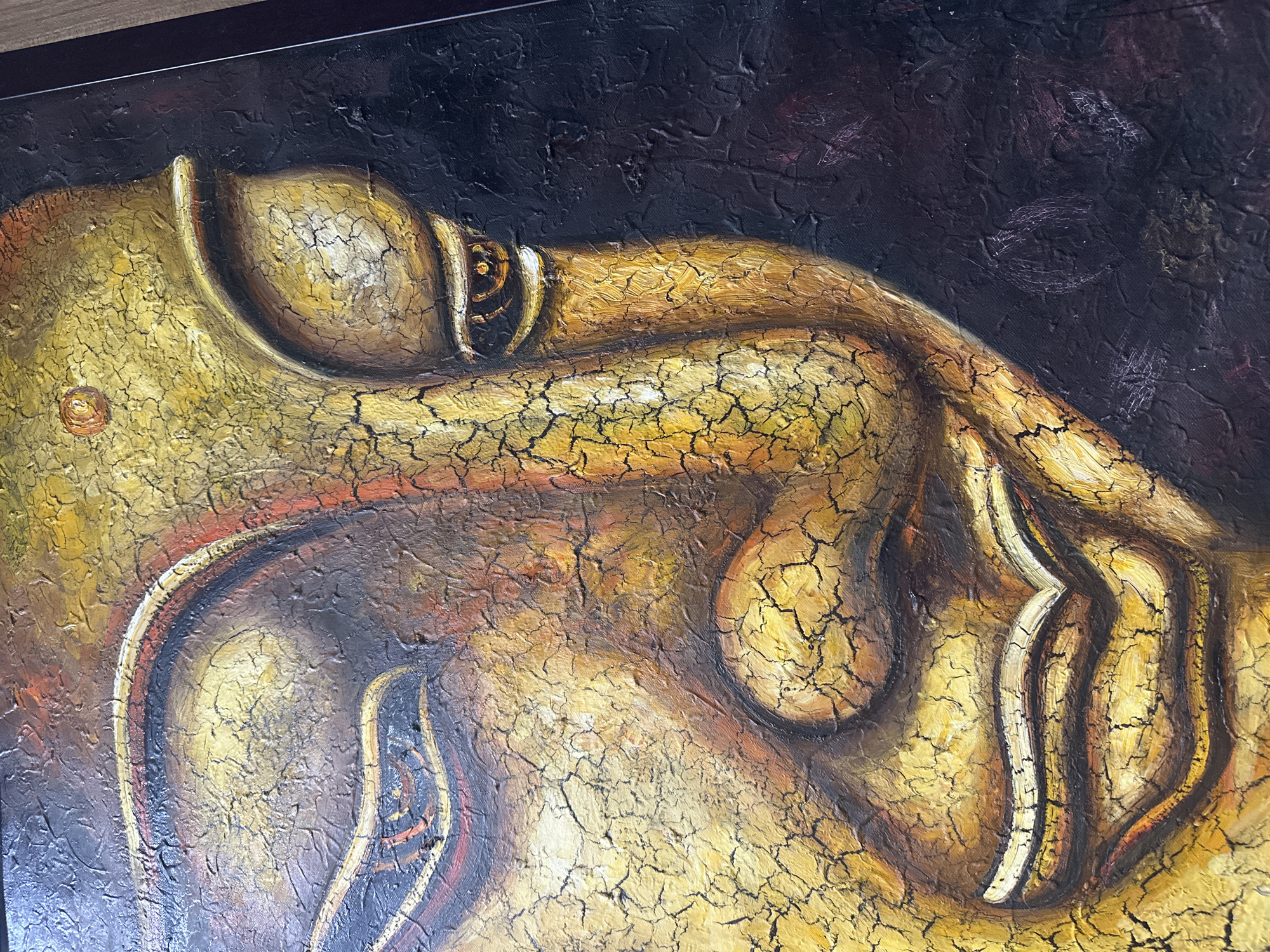 The image shows a close-up of a textured painting, likely an oil painting, of a reclining or sleeping Buddha. The figure is rendered in shades of gold, brown, and tan, with heavy cracking throughout the painted surface. The background is a dark, textured color, probably black or a very dark brown. A black frame partially surrounds the top and left sides of the painting. The location is unspecified and there is no mention of Nha Trang Ward or Vietnam.