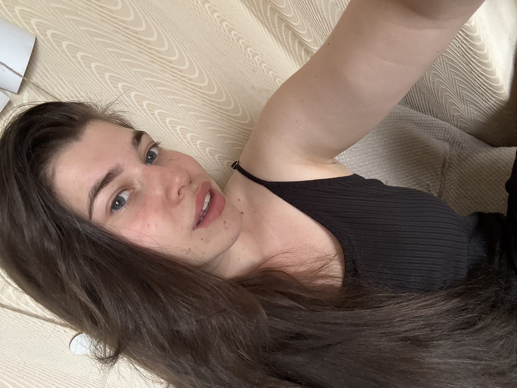 A young woman with long, dark brown hair is lying on a patterned, beige surface. She is wearing a black top. The location is not discernible as Мещёры, Russia.