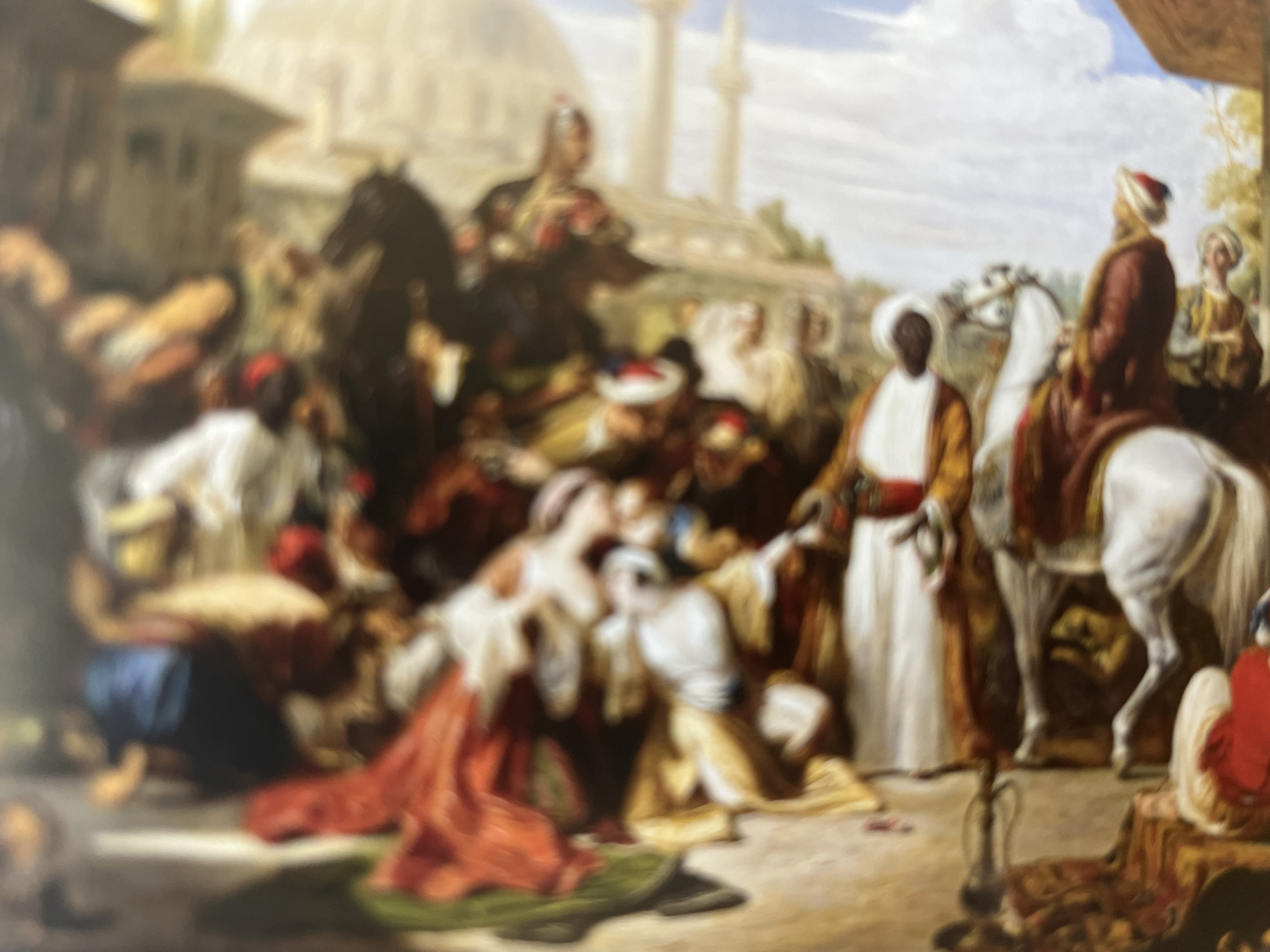 The image depicts a bustling scene with multiple figures in opulent attire, suggesting a historical or cultural event in an indeterminate urban setting. The overall impression is one of grandeur and activity, with a variety of colors and textures contributing to a rich visual tapestry.
In the foreground, several individuals are engaged in various activities. One person, wearing a white turban and a rich maroon robe, appears to be either sitting or standing near a white horse. This figure's hand is extended, holding a small, round object that might be a fruit or decorative item. Another figure, partially obscured, wears a white garment and a red head covering. To their left, a person in a blue garment is visible, along with elements of what could be tents or awnings in muted earth tones.
Further back, the scene unfolds with more figures and architectural elements. A prominent red fabric is draped across some individuals, adding a vibrant splash of color. The figures are depicted in dynamic poses, suggesting movement and interaction within the gathering. The background reveals hints of buildings with domes and arches, characteristic of Middle Eastern or Mediterranean architecture, with a pale blue sky visible above. The style of dress—turbans, robes, and head coverings—reinforces a sense of historical or exotic setting. The lighting suggests a bright, sunny day, casting shadows that contribute to the depth and dimensionality of the scene. The composition is crowded, with figures overlapping and creating a sense of a dense, active populace.