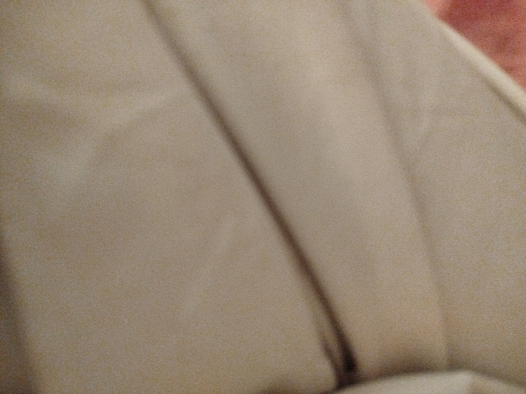 The image shows a close-up of a beige, textured fabric. The fabric is draped, creating soft folds and shadows. There are no discernible objects, people, or any identifiable features within the image that could indicate a specific location, including Lassan, Pakistan. The image appears to be a detail shot of a textile.