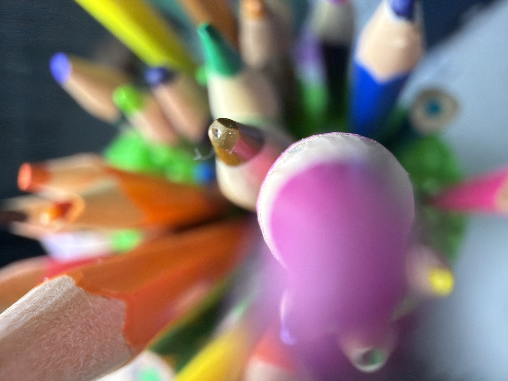The image is a close-up shot of a collection of colored pencils. The pencils are clustered together, with various colors visible, including pink, orange, yellow, green, blue, and brown. The tips of the pencils are in varying degrees of focus, with some appearing sharp and others blurred. The image does not contain any information to determine a location or the city of Votkinsk, Russia. The image does not include any people, actions, or interactions. The focus is solely on the pencils and their arrangement.