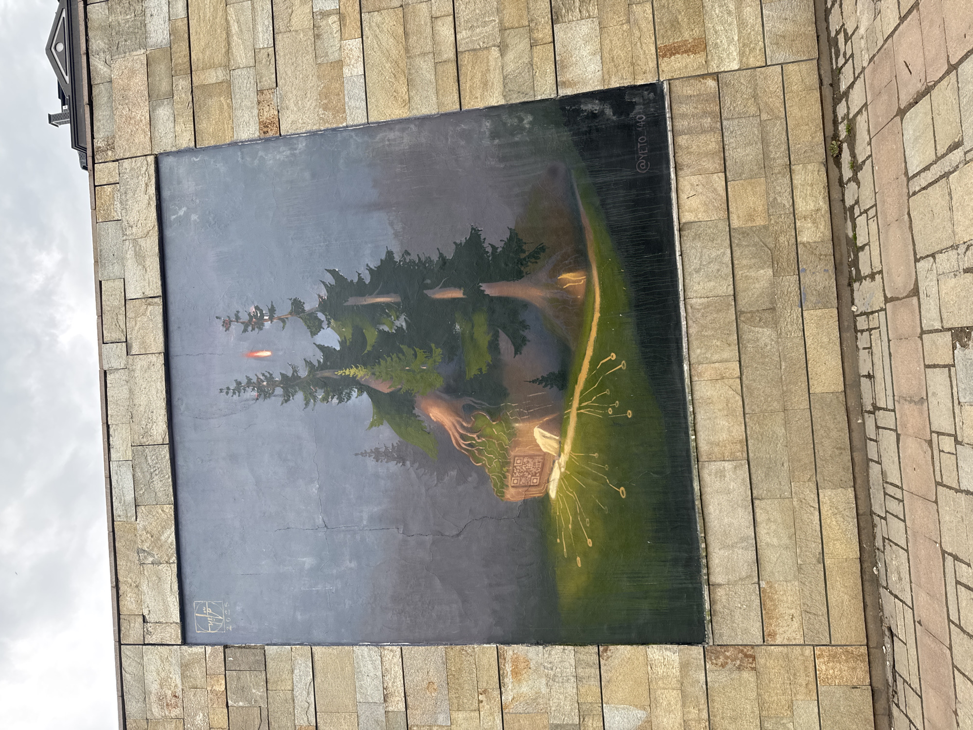 A mural is affixed to a building constructed with rectangular stone blocks. The mural depicts a landscape with trees, a small structure with a QR code visible, and illuminated lines extending from the structure. The mural is bordered by the stone blocks, and a signature and date ("2023") are visible on the lower left corner of the mural. The artist's name, "@YETO_440," is visible on the upper right of the mural. The mural appears to be located in Sofia, Bulgaria.