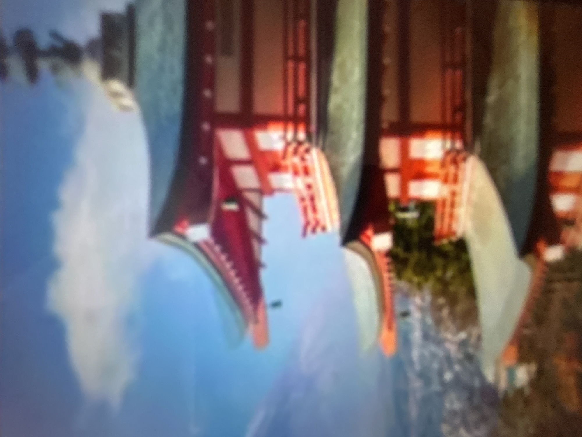 The image depicts a blurry, upside-down scene with elements suggestive of a traditional East Asian architectural style, possibly a temple or a pavilion. The dominant colors are red, white, blue, and green. In the foreground, there are large, curved structures that appear to be part of the architecture, painted in red and white with intricate patterns. These structures seem to be supported by large, light-colored pillars or columns.
The background is a bright blue, possibly representing the sky, with some white streaks that could be clouds or mist. There are also hints of green foliage and water, suggesting an outdoor setting. The overall impression is one of grandeur and possibly a serene or mystical atmosphere, despite the blurriness of the image. No people are clearly visible, nor is any specific activity taking place. The lighting is bright, indicating it is daytime, but the weather is not discernible. There is no visible text in the image. The provided location context of Gelendzhik, Russia, does not align with the visual cues of the image, which strongly suggests an East Asian aesthetic.