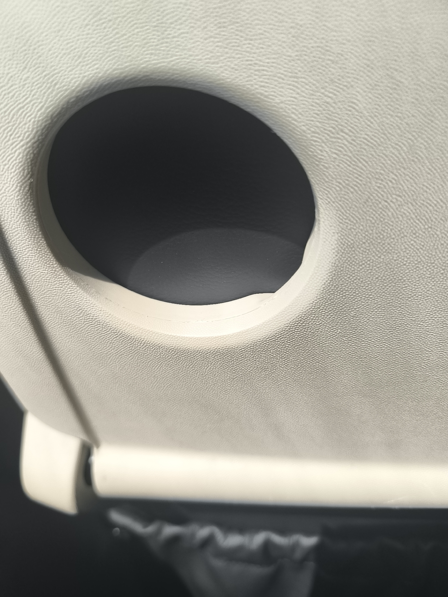The image shows the inside of a vehicle, specifically a tan-colored panel with a circular opening. The panel has a textured surface. Below the panel, a hinge mechanism is visible. The circular opening reveals a dark, possibly black, interior space. The location of the image in Saint-Chamond, France cannot be determined from the content of this image.