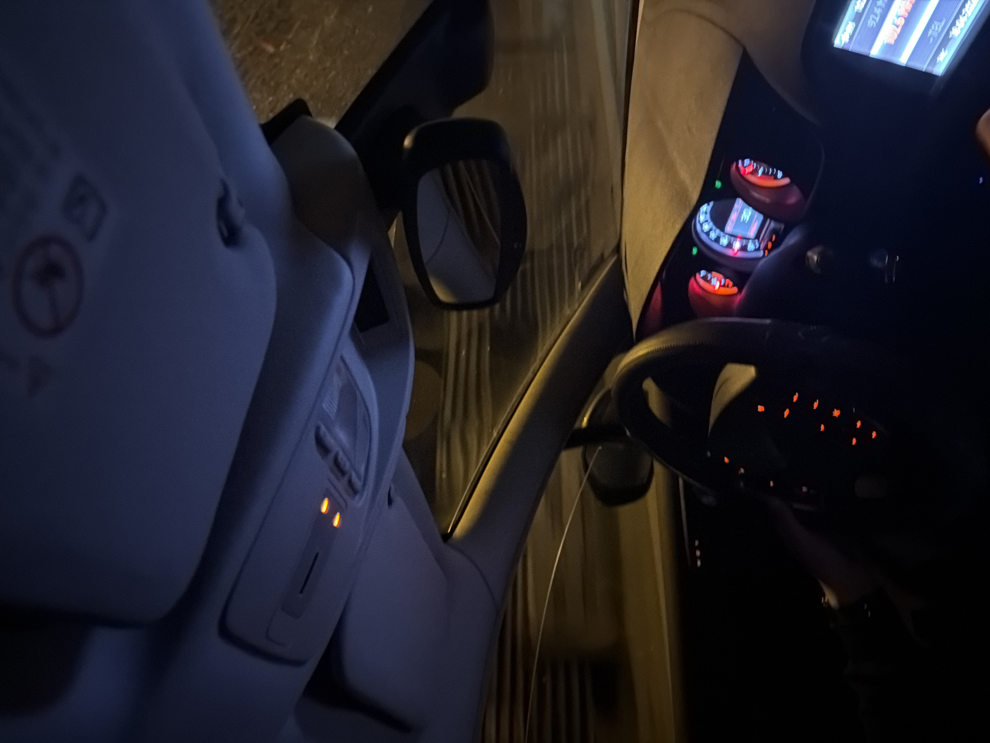 The image shows the interior of a car, specifically the driver's side. The dashboard and steering wheel are visible, illuminated by the instrument panel lights. The rearview mirror and part of the passenger seat are also in the frame. The environment outside the car appears dark, possibly indicating night. The location is uncertain, and there is no information to definitively place it in Sofia, Bulgaria.