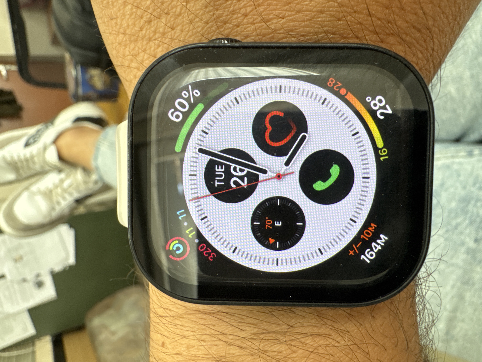 A close-up shot of an Apple Watch on a person's wrist. The watch face displays various complications, including battery percentage (60%), temperature (28°), date (Tuesday the 26th), direction and inclination. Given the presence of both Celsius temperature readings and Cyrillic characters on the image, but not on the watch face, the watch could be in Bulgaria or another country that uses the Cyrillic alphabet. Since the prompt asks for the location of Plovdiv, Bulgaria, this cannot be verified from the image.
