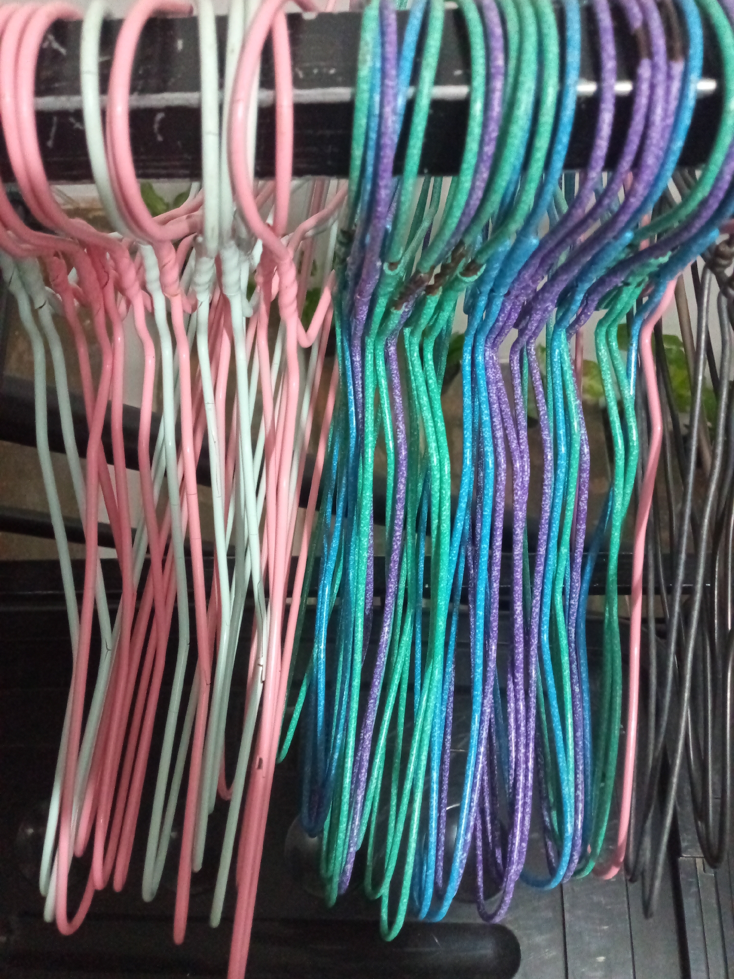 The image shows a close-up view of several clothes hangers hanging on a rack. On the left side of the image are pink and white plastic hangers. The hangers on the right are multi-colored, with shades of green, blue, and purple. The location in the city of Davao City, Philippines, is not determinable from the visual data.