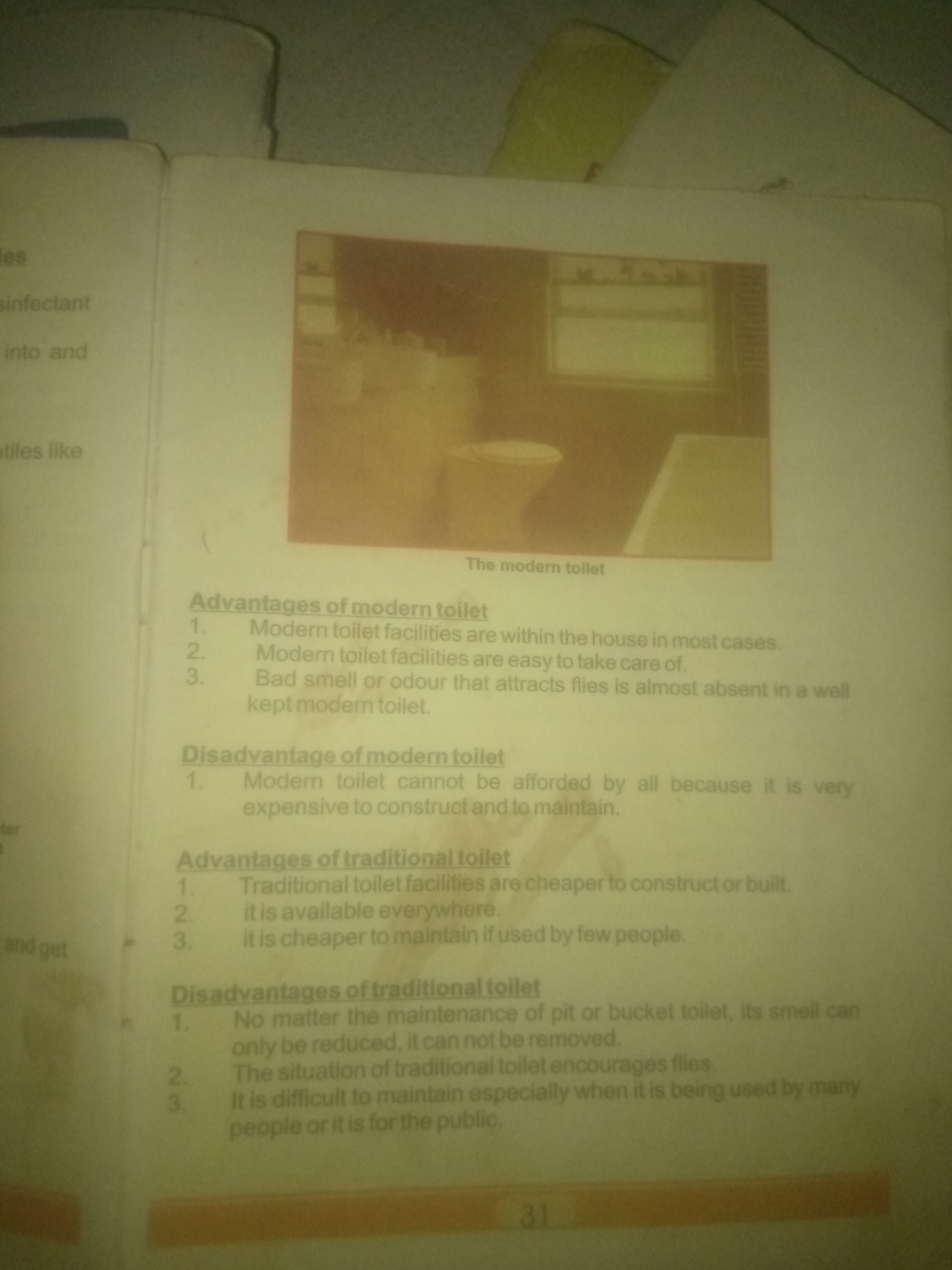 The image is a close-up shot of a page from a book, featuring text and an illustration related to toilets. The text is divided into sections discussing "Advantages of modern toilet," "Disadvantage of modern toilet," and "Advantages of traditional toilet," as well as "Disadvantages of traditional toilet." Each section is followed by a numbered list of points.
The illustration at the top of the page depicts a modern bathroom interior with a toilet. The caption below the illustration reads "The modern toilet."
There is no information in the image that indicates its location in the city of Jauro Yinu, Nigeria. The image is a static depiction of printed material and does not contain any elements related to a specific geographic location or a real-world scene in Jauro Yinu, Nigeria. Therefore, a description of the scene in Jauro Yinu, Nigeria, cannot be provided based on this image.