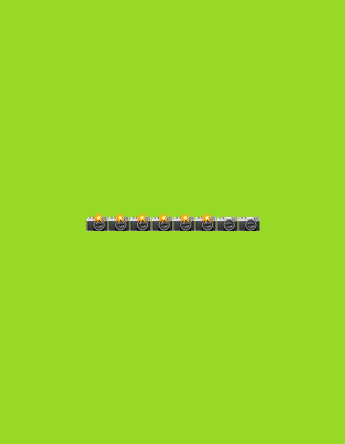 The image displays a plain, vibrant lime green background. Centered horizontally near the bottom of the frame, a series of eight identical camera emojis are arranged in a straight line. Each camera emoji is depicted in grey with a silver lens and features a bright yellow flash emanating from above the lens. The cameras are facing forward, and their flashes are all active. There are no people or any other discernible objects present in the image. The location in Gorzow, Poland, is not evident from the image.