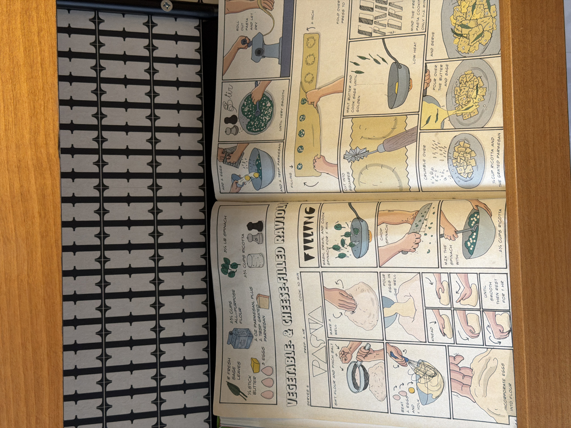 The image shows an open cookbook with a recipe for vegetable and cheese-filled ravioli. The cookbook is placed on a wooden surface next to a black and white patterned object with geometric shapes. The recipe includes instructions and illustrations on how to make the pasta and filling, including ingredients such as fresh sage, butter, eggs, flour, parmesan, spinach, and ricotta. The instructions cover steps like sifting flour, making a well, kneading, and cooking the spinach. The images show techniques such as rolling out pasta, filling it, cutting it into squares, and serving with melted butter and sage. The location in the city of Tbilisi, Georgia is not indicated in the image.