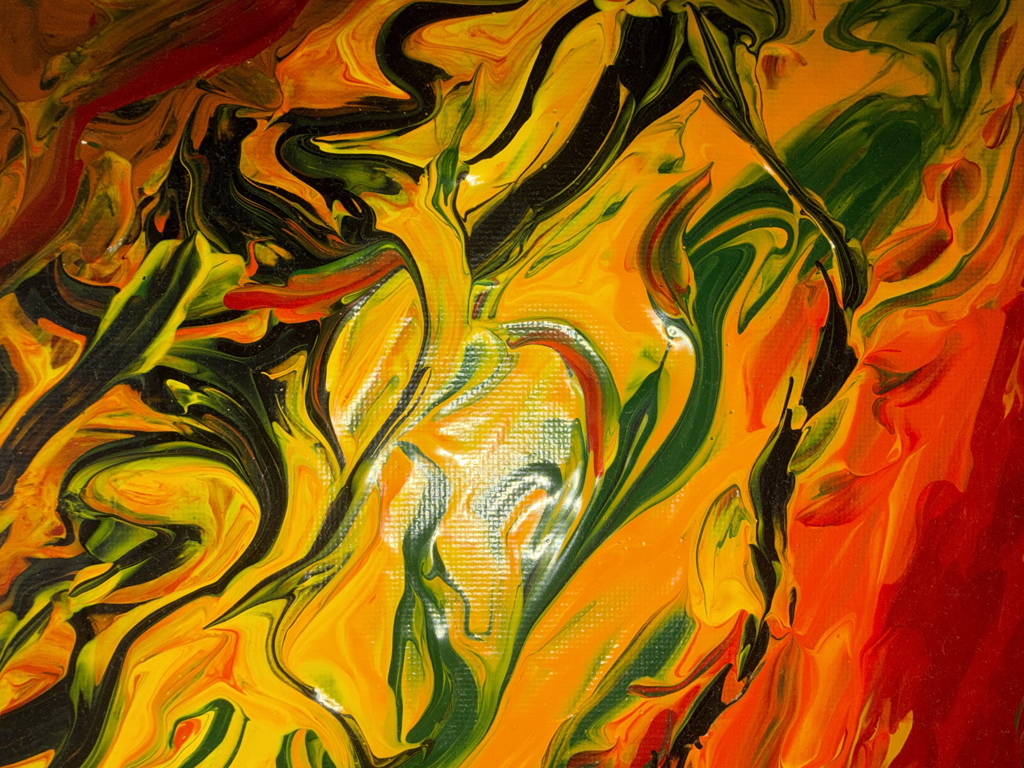 This is an abstract acrylic pour painting featuring vibrant swirls of yellow, orange, red, green, and black paint. The paint is thick and textured, creating a dynamic, flowing effect. There are no people, identifiable objects, or discernible locations within the image. The texture of the canvas is visible in some areas.