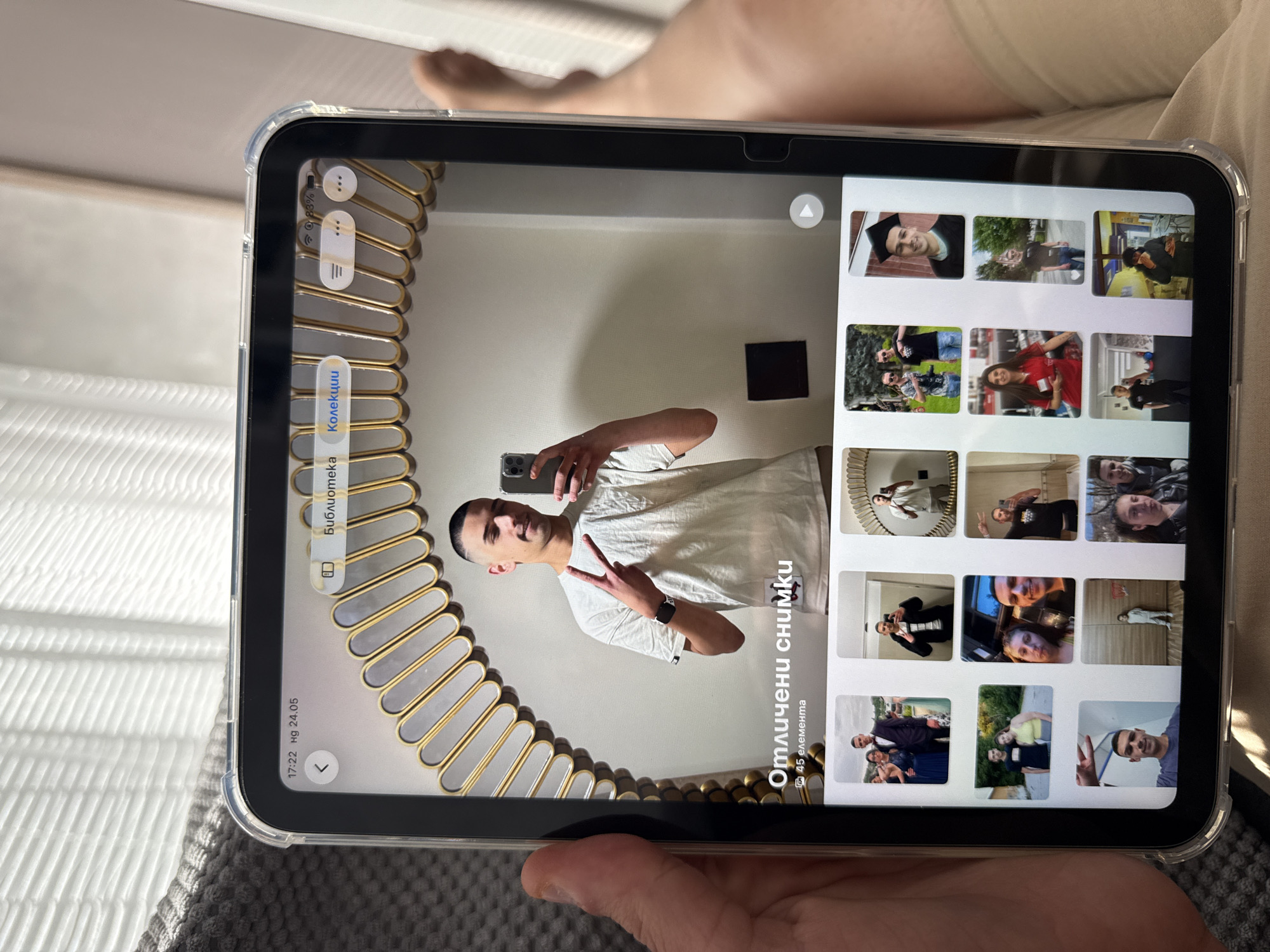 The image shows a person holding a tablet displaying a gallery of photos. The photos seem to depict various people in different settings. In the main image on the tablet, a man is taking a selfie in front of a decorative mirror. The tablet also displays user interface elements in a language other than English. The location of the city of Lovech, Bulgaria, is not visually discernible in the image.