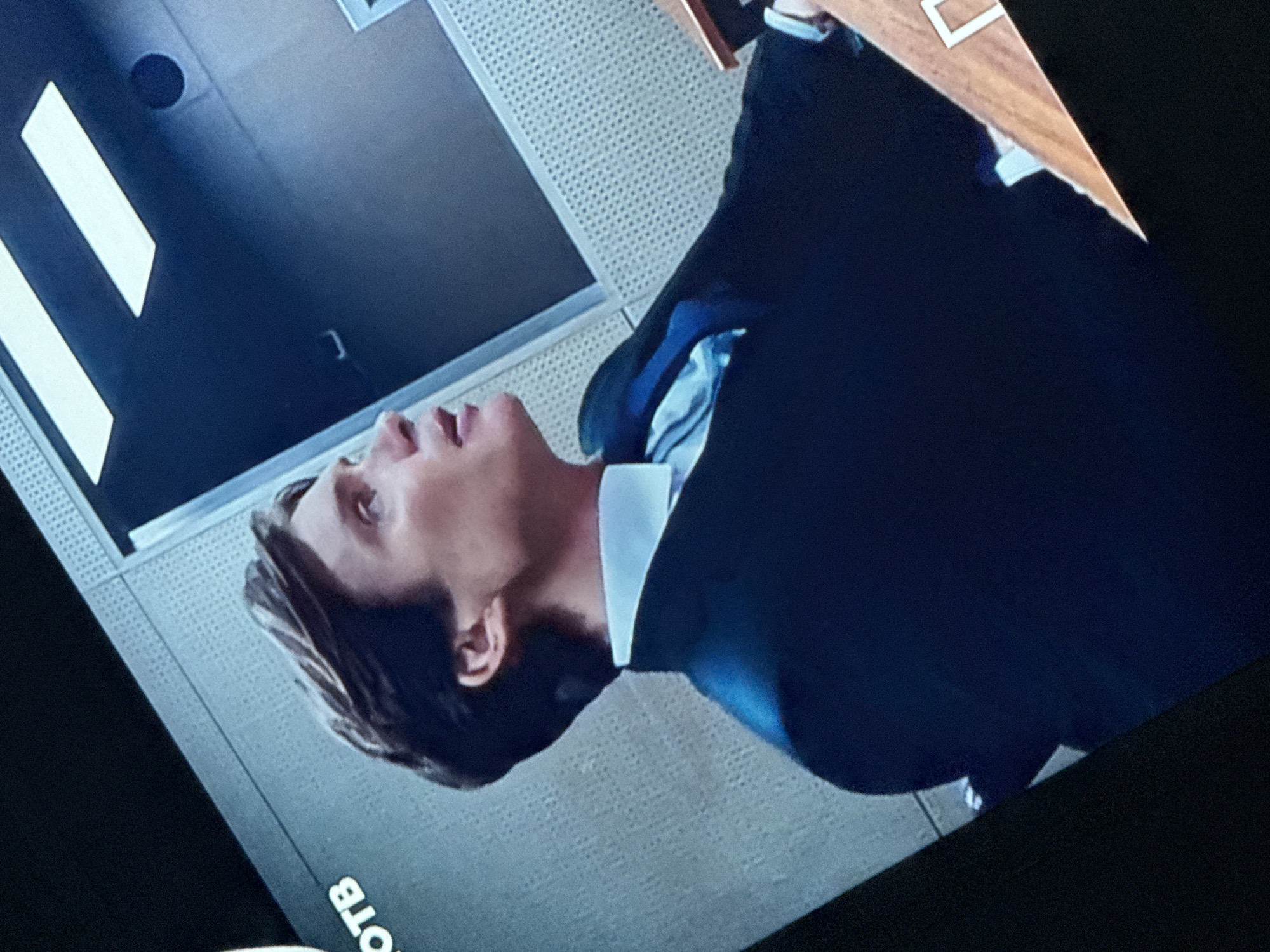 A man in a dark suit and white shirt is seen in profile, head turned upwards and slightly to the left. He appears to be indoors, as evidenced by the ceiling panels in the background. The setting appears to be a modern office space. The city of Mytishchi, Russia is not discernible from the given image.
