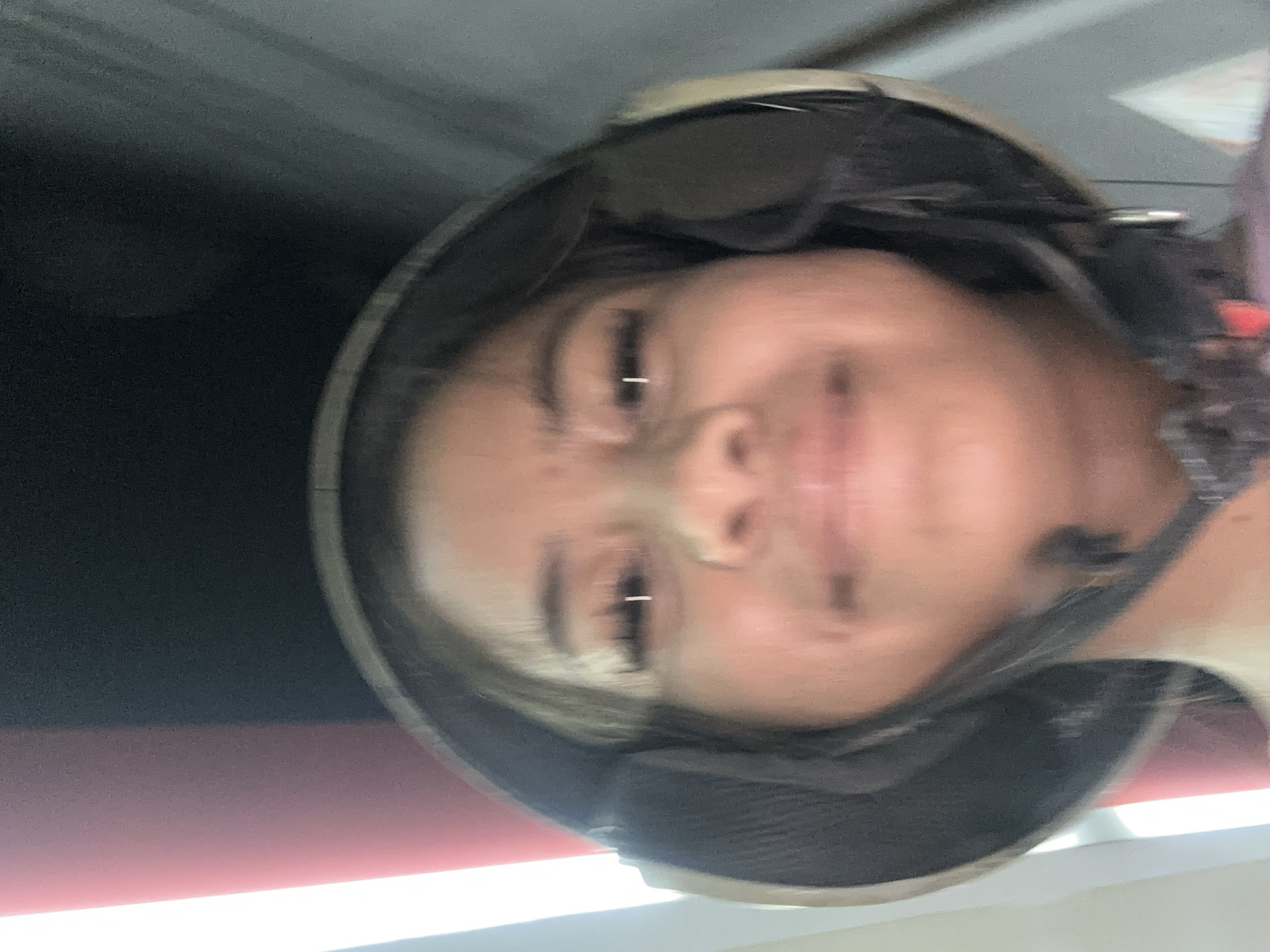 A close-up, blurred image depicts a person wearing a helmet. The subject is centered in the frame, with their face visible inside the helmet. The background consists of indistinct shapes and colors, including a red and black area. There is no clear indication of the location being Central Jakarta, Indonesia.