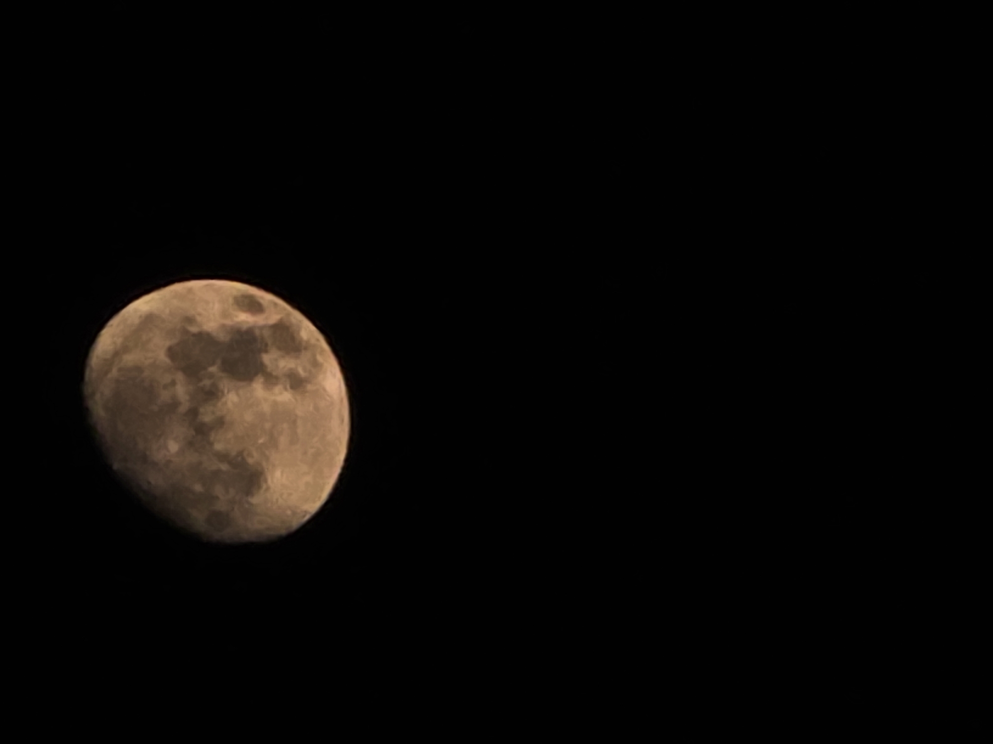 The image displays a close-up view of the moon against a black, starless sky. The moon is partially illuminated, showing a texture of craters and lunar features. The lighting suggests it is either a crescent or gibbous phase. There is no indication of the city of Shulavery, Georgia, or any other terrestrial elements within the frame.
