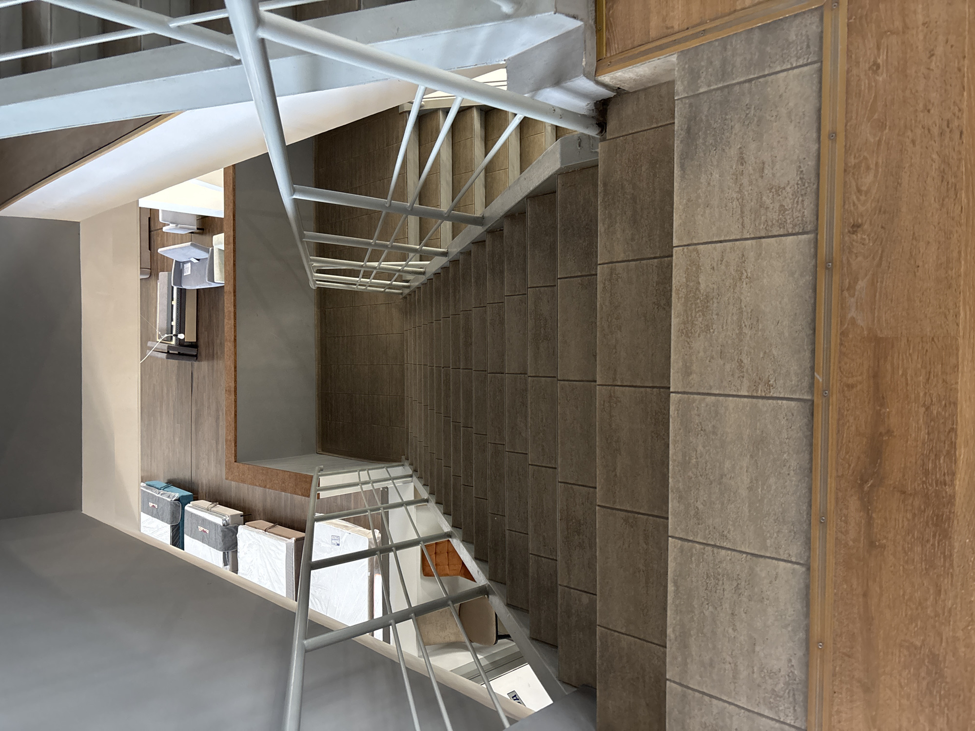 The image shows an indoor staircase with a gray railing and beige tiled steps. The staircase leads down from a mezzanine level where mattresses and furniture are displayed. In the background, there is a view of a furniture store or showroom. The lighting is bright, suggesting an interior commercial space. The location is identified as Zaporizhzhia, Ukraine.