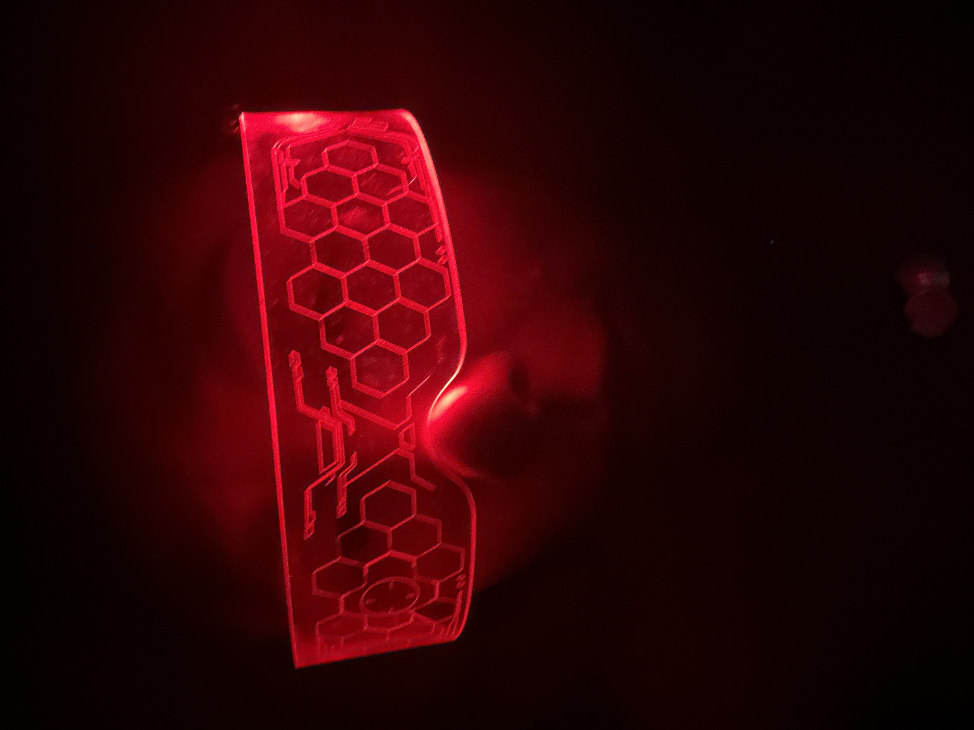 A close-up photograph shows a translucent material illuminated with red light, displaying a pattern of hexagons and circuit-like lines. The background is dark and obscured, creating a stark contrast with the brightly lit object. There is no visible indication in the image that specifies a location, including Votkinsk, Russia. There are no other objects or people visible.