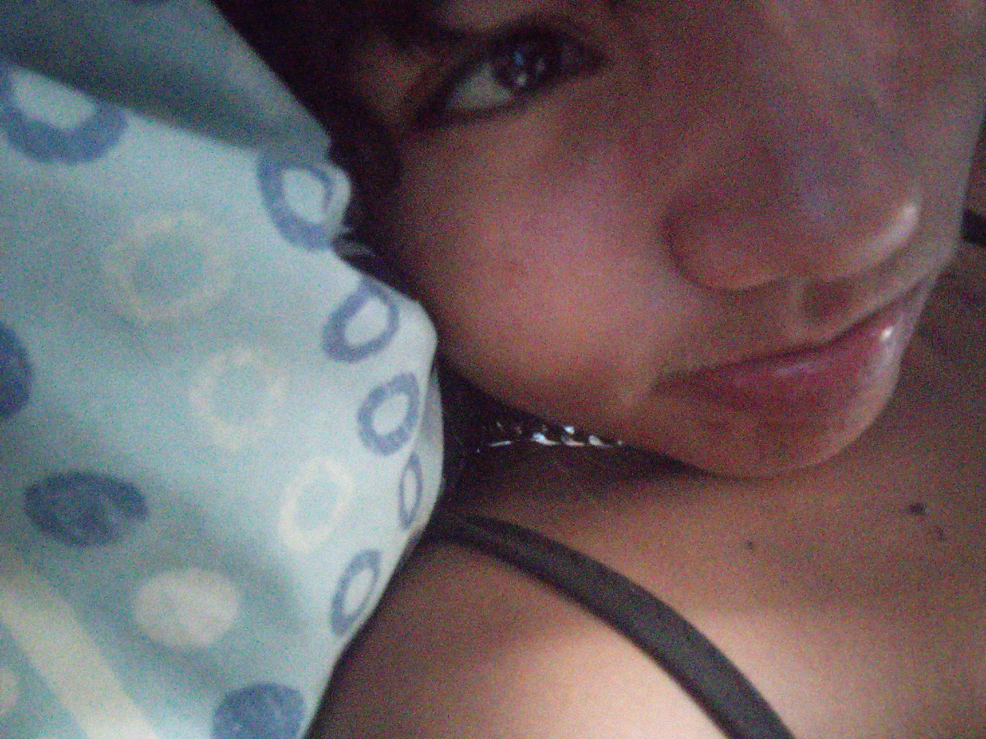 A close-up, grainy photograph depicts a person lying on a light blue pillow with a polka dot pattern. The person's face is visible, showing their eye, nose, and mouth. Part of their shoulder and the strap of an undergarment are also visible. The image does not provide information about the location in Juan Griego, Venezuela.