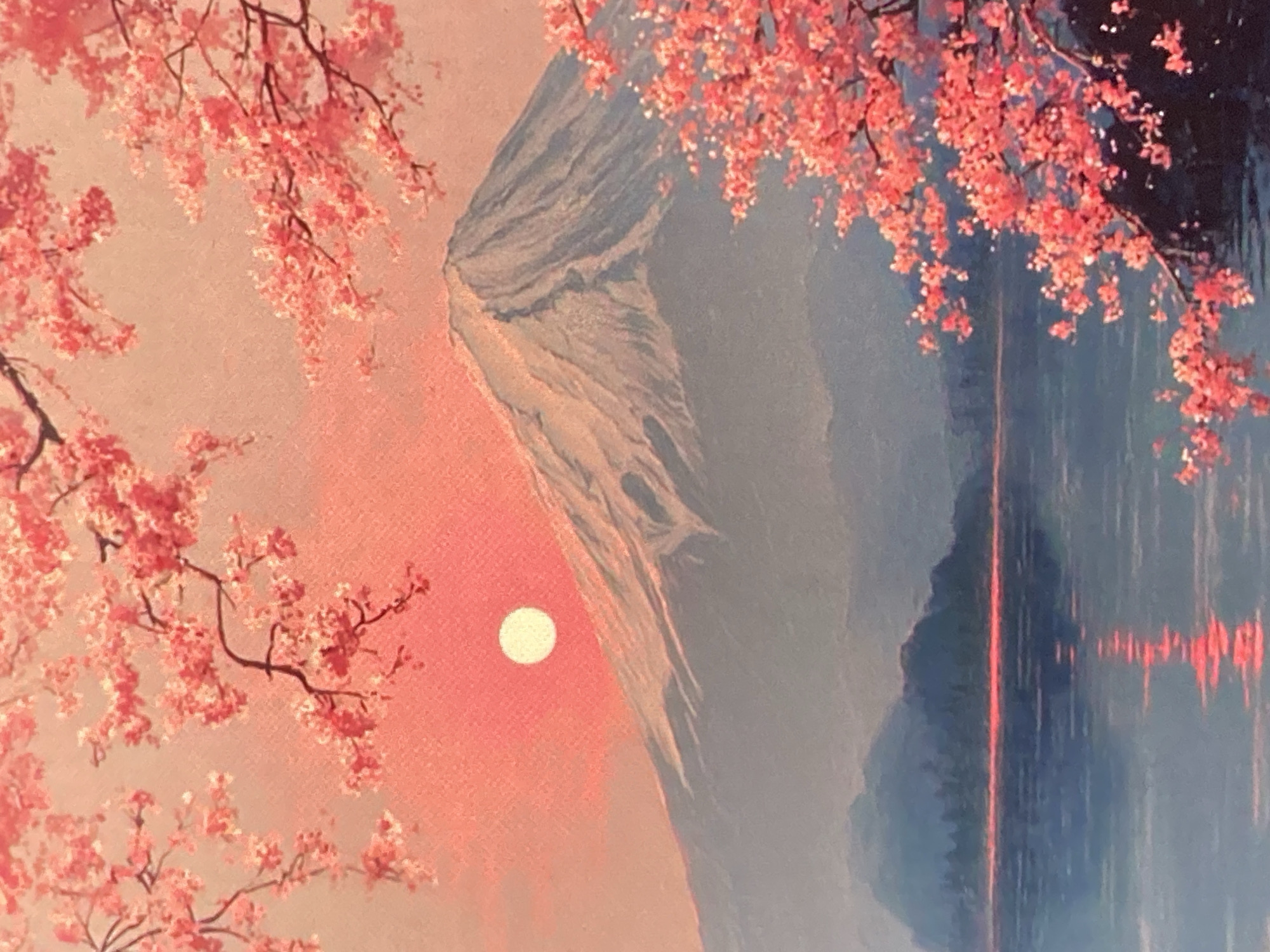The image depicts a serene natural landscape painting. A prominent snow-capped mountain, likely Mount Fuji, dominates the background, bathed in the warm glow of a setting sun. The sky is a vibrant blend of pink and orange hues. In the foreground, branches adorned with delicate pink cherry blossoms frame the scene, their reflection shimmering on the tranquil surface of a lake. Distant, hazy blue mountains form a layered backdrop to the water. The overall impression is one of natural beauty and tranquility. There is no identifiable location in the city of Ustyvytsia, Ukraine depicted in this image.