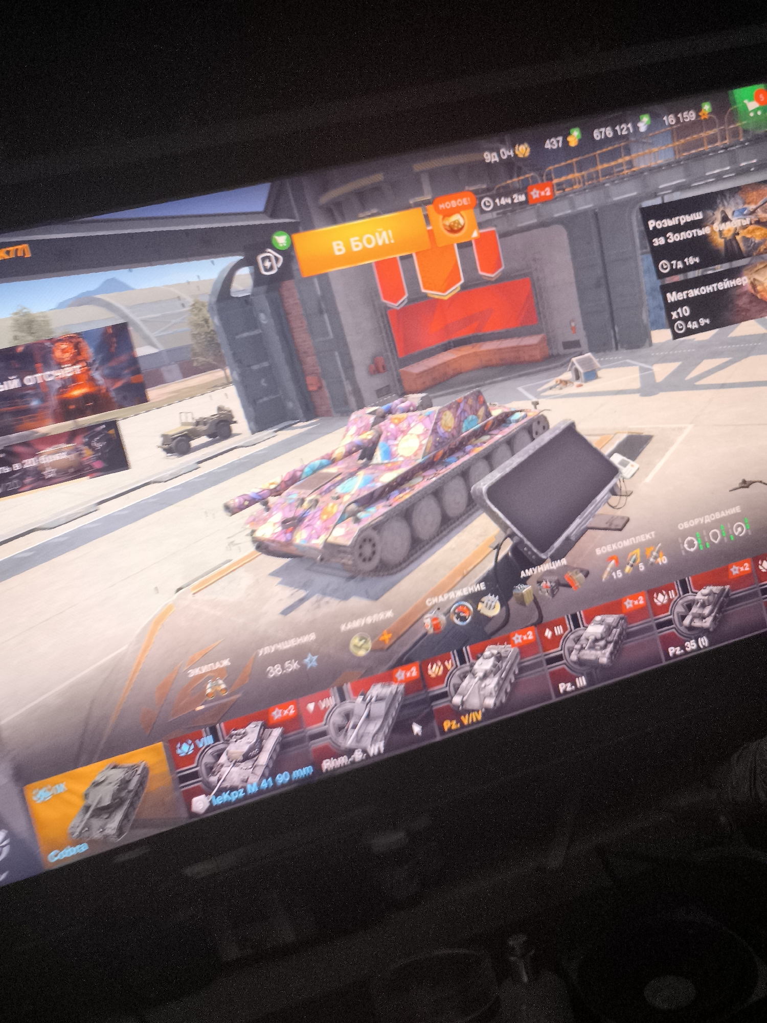 This image shows a computer screen displaying the video game "World of Tanks". The game interface is visible, with a tank in the center of the screen and various menus and icons around it. There are also elements of the game's user interface, such as currency, experience points, and time remaining for certain events. The background of the game appears to be a battlefield or garage environment. The image quality is poor, likely due to being taken with a phone camera at an angle, resulting in blurriness and glare. There is no indication or information within the image that suggests a location in the city of Riga, Latvia.