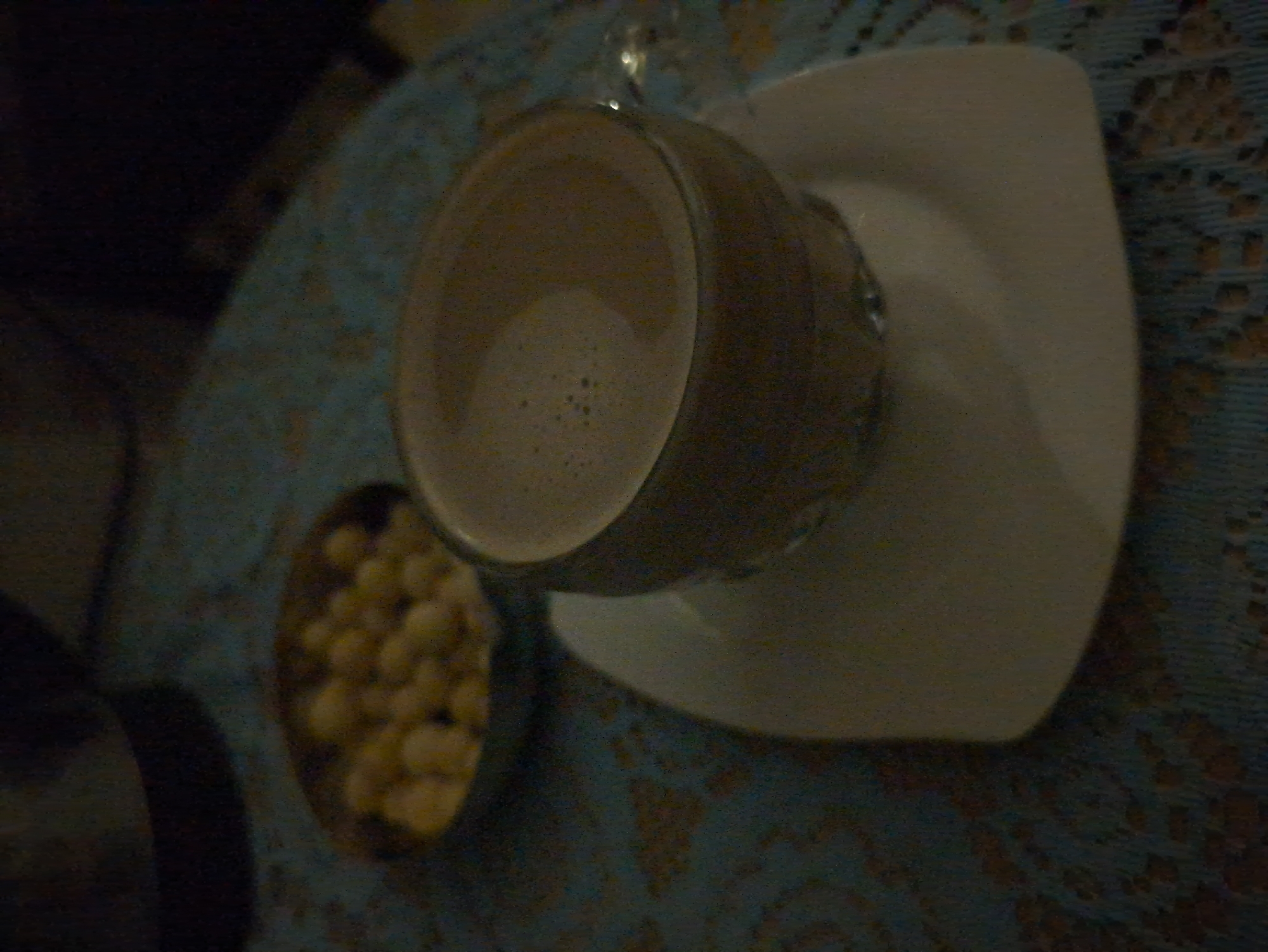 A cup of coffee sits on a white square saucer. A small bowl of roasted chickpeas is also visible. They are set on a blue tablecloth. The location is in South Quy Nhon Ward, Vietnam.