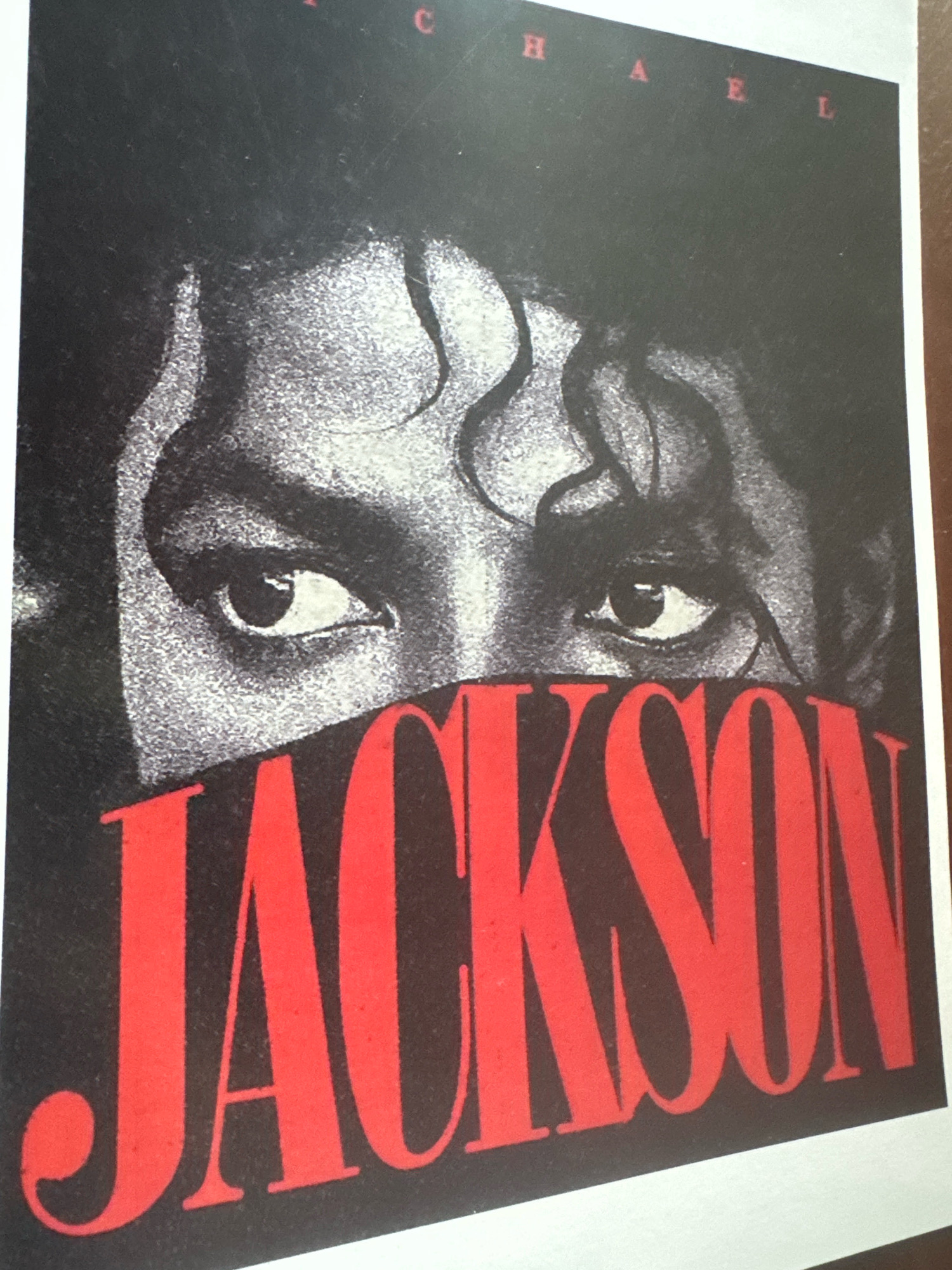 The image is a close-up of a poster featuring a black and white photograph of Michael Jackson's eyes and the word "JACKSON" in large red lettering. The text "MICHAEL" is visible in red capital letters above his eyes. The poster appears to be made of paper and is slightly worn. There are no visible indications of the city of Hyderabad, India, or any other specific location. The image focuses solely on the graphic design elements of the poster.