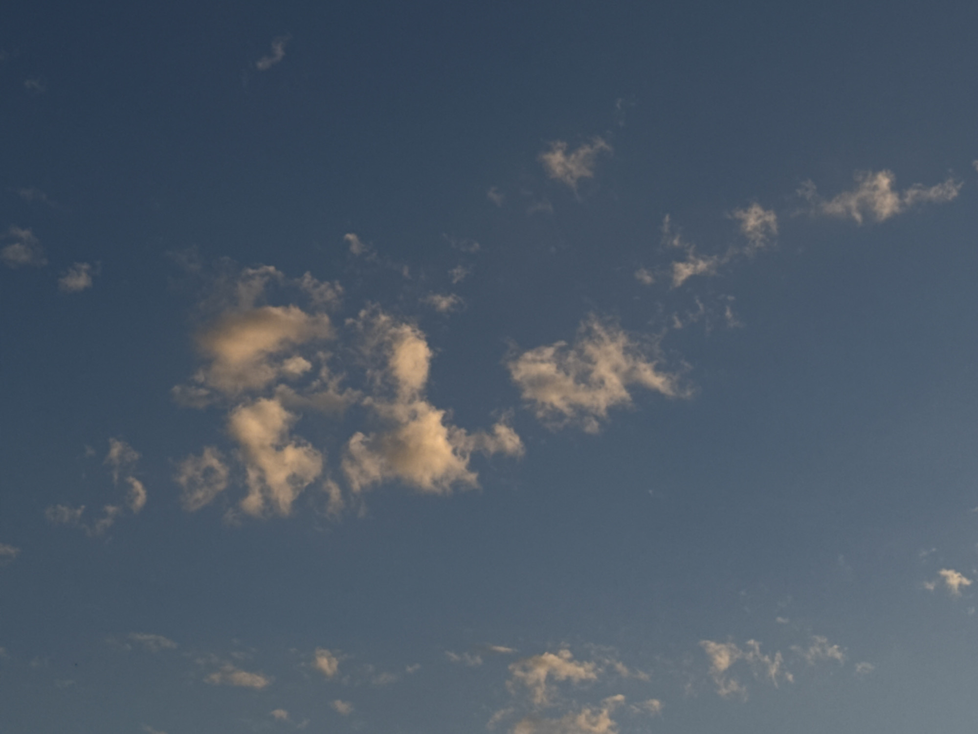 The image shows a view of the sky, with scattered clouds against a blue background. The clouds vary in size and density, with some appearing brighter and more defined than others. The overall lighting suggests it is either early morning or late afternoon. The image doesn't provide any information about the location in Chaikovsky, Russia, or include any details about people, actions, or objects that can be analyzed.