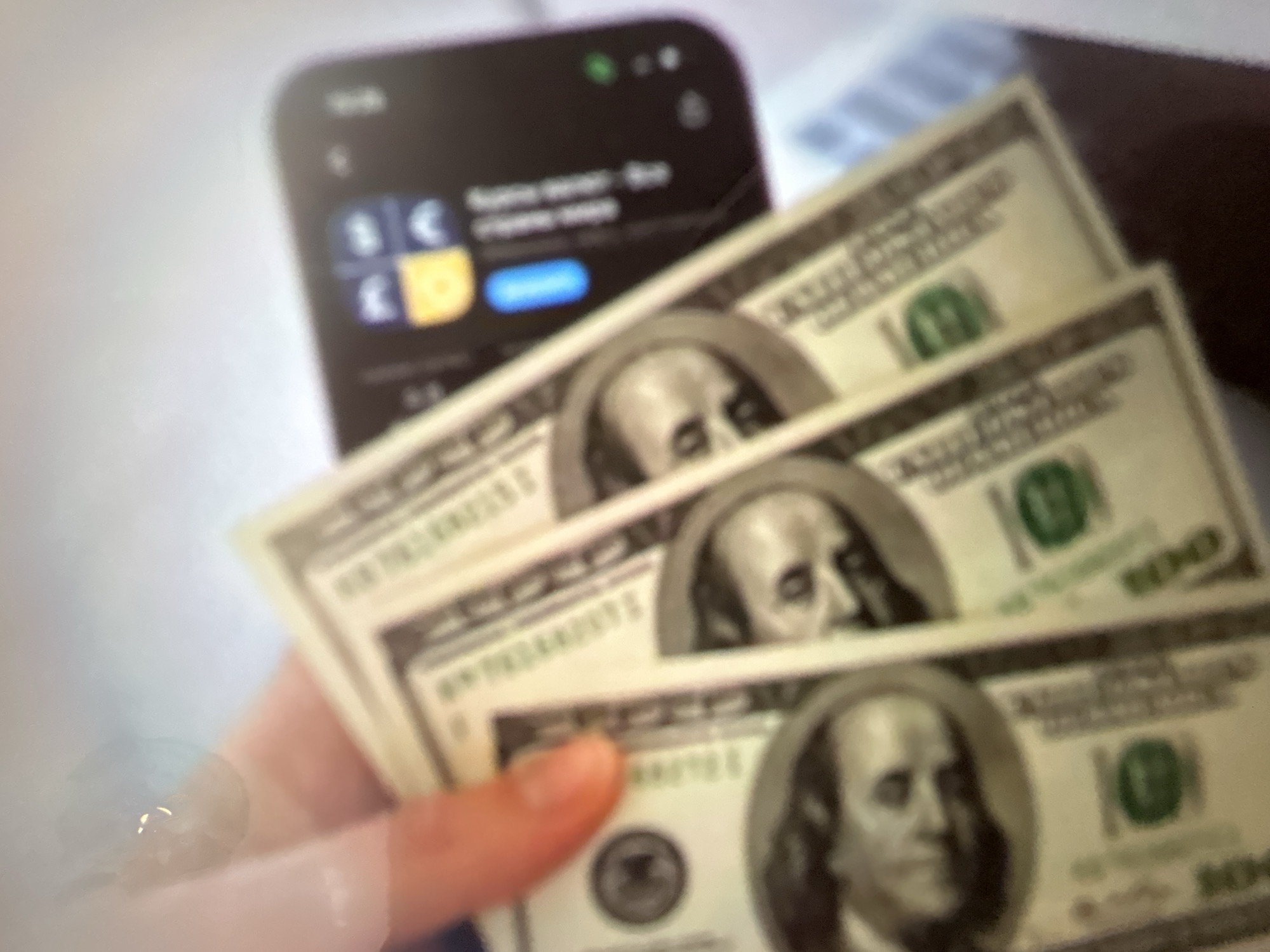 The media file features a close-up shot of several US hundred-dollar bills held by a person's hand. The bills are stacked, with the top one partially obscuring the ones below it. The faces of Benjamin Franklin are visible on each bill. In the background, a smartphone is slightly out of focus, displaying icons that suggest a currency exchange or financial application, with symbols for the Euro (€) and Pound Sterling (£) visible. A blue button is also visible on the phone screen.
The scene appears to be indoors, likely a casual setting given the close-up nature of the shot. The lighting is not distinct enough to determine the time of day or weather conditions. The overall impression is one of financial transactions or a demonstration of wealth. The blurry nature of the background elements, particularly the phone, suggests the focus is intended to be on the money. There is no discernible text beyond what is printed on the currency and the limited, blurry text on the phone screen. The emotion conveyed is ambiguous, but the emphasis on money might suggest themes of investment, profit, or savings.
The provided location context, Gelendzhik, Russia, offers no direct visual cues within the image itself to confirm or deny this setting.